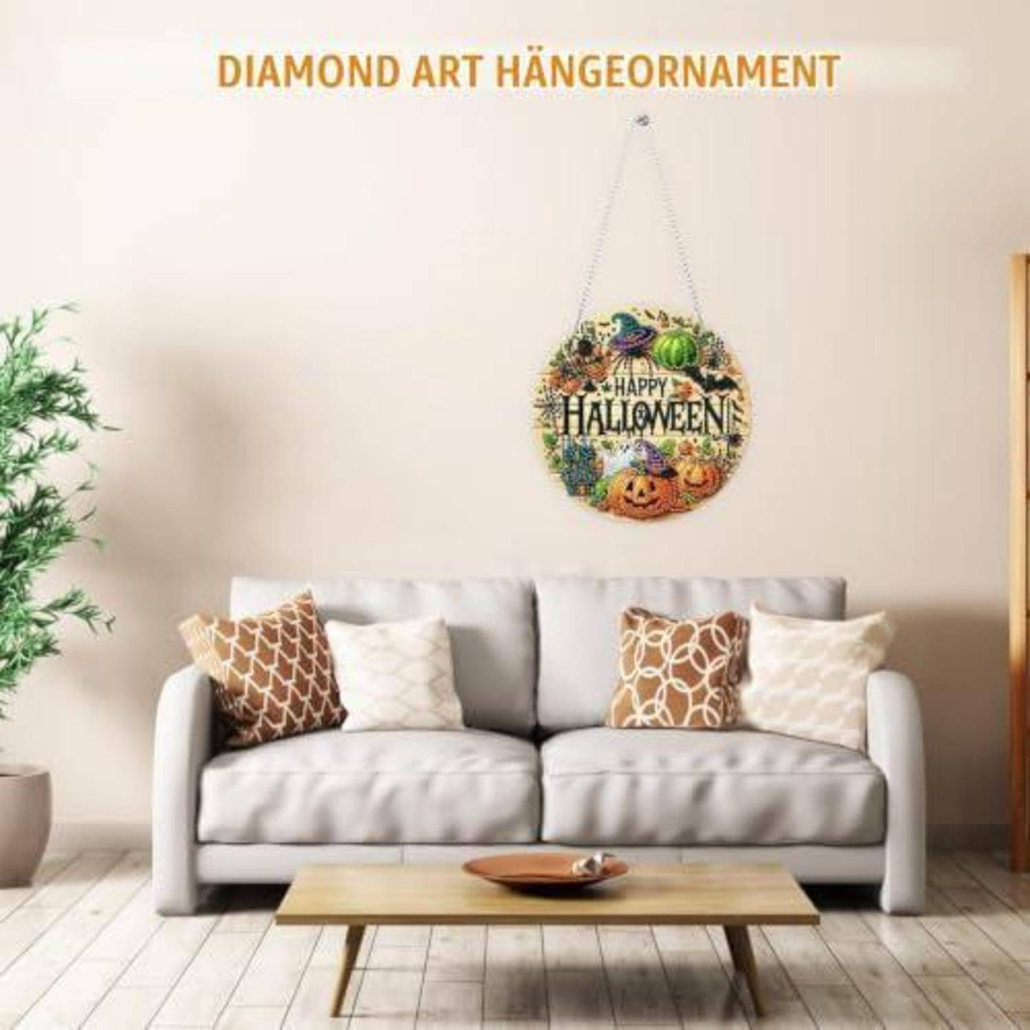 Wohnzimmer mit einem grauen Sofa und Kissen unter einer hängenden runden Diamantkunst-Dekoration mit der Aufschrift „Happy Halloween"; der Text oben lautet „DIAMOND ART HÄNGORNAMENT"".