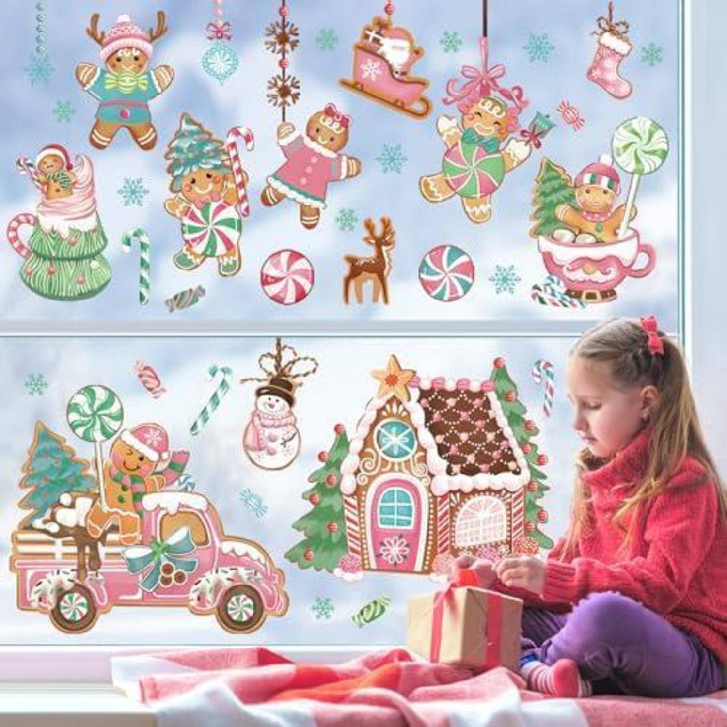 Ein Mädchen, das neben einem Fenster sitzt, öffnet ein Geschenk neben weihnachtsthematischen Aufklebern von Lebkuchenmännchen, Zuckerstangen, Schneeflocken, einem Rentier, einem Auto und einem Süßigkeitenhaus.