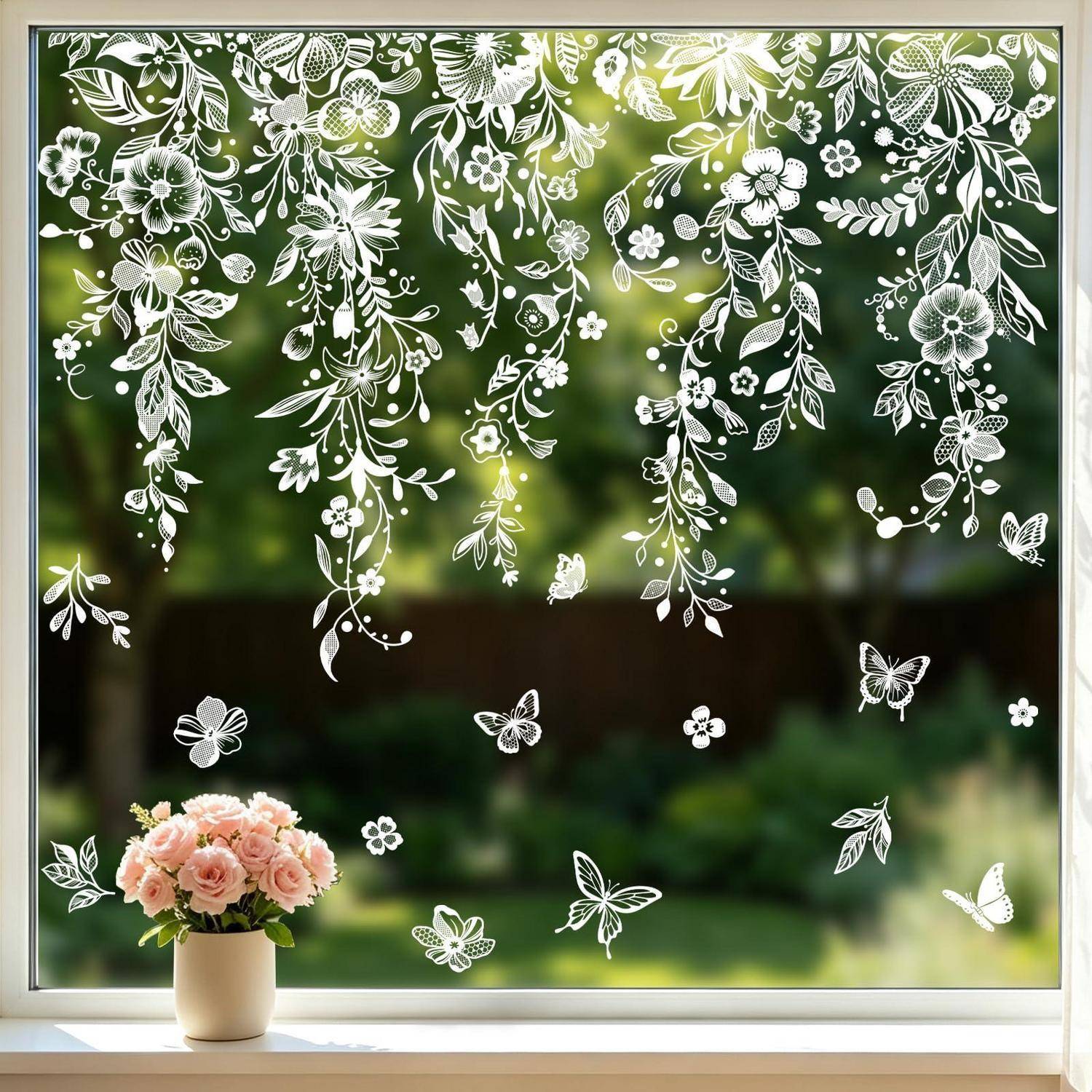 Weiße Blütendekor verziert ein Fenster über einer kleinen Vase mit rosa Rosen, mit verschwommenem grünen Gartenszenario außerhalb.