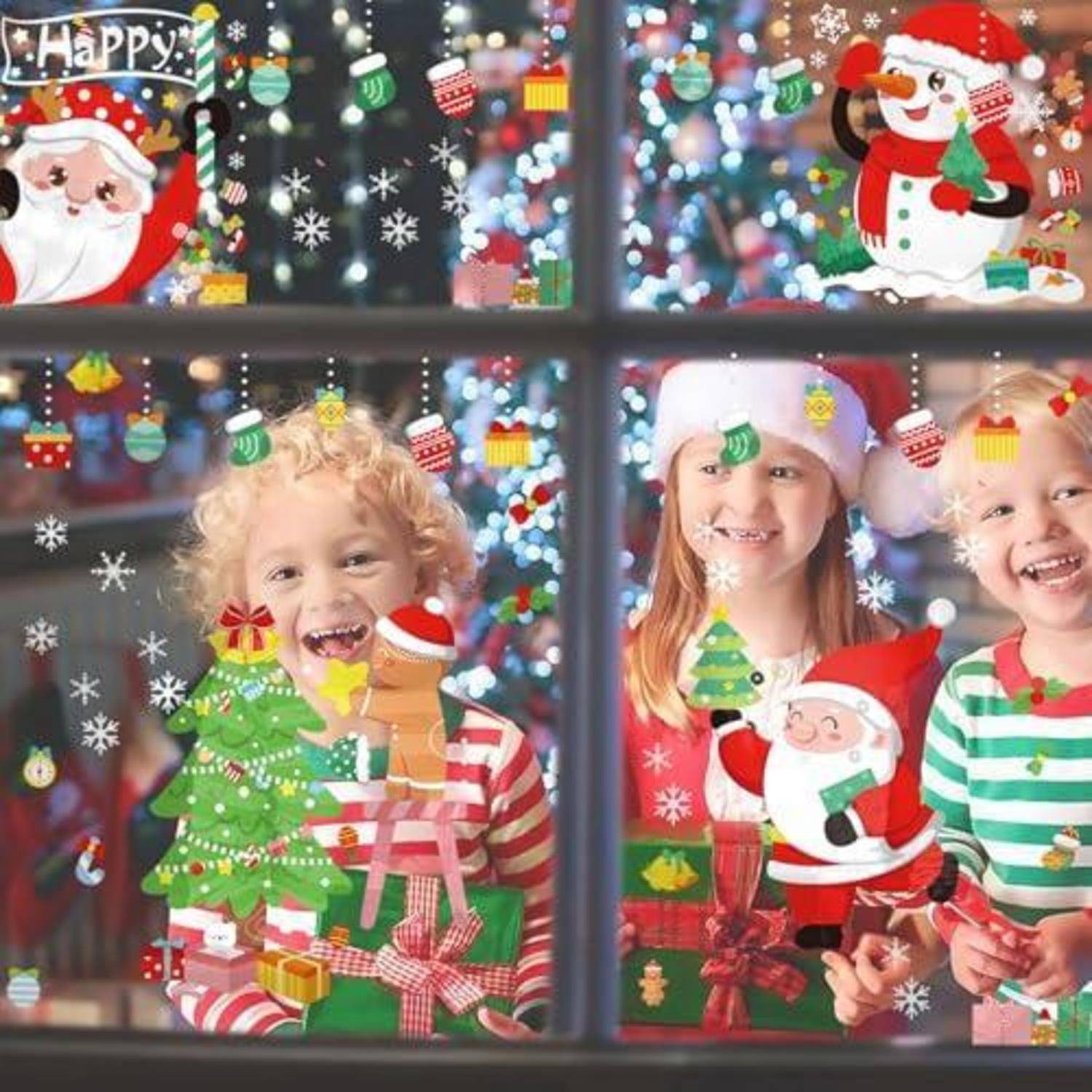 Kinder, die hinter einem mit Weihnachtsstickern dekorierten Fenster lächeln, halten Feiertagsgeschenkboxen in den Händen, mit Bildern von dem Weihnachtsmann und Schneemännern sowie dem Text „Happy".