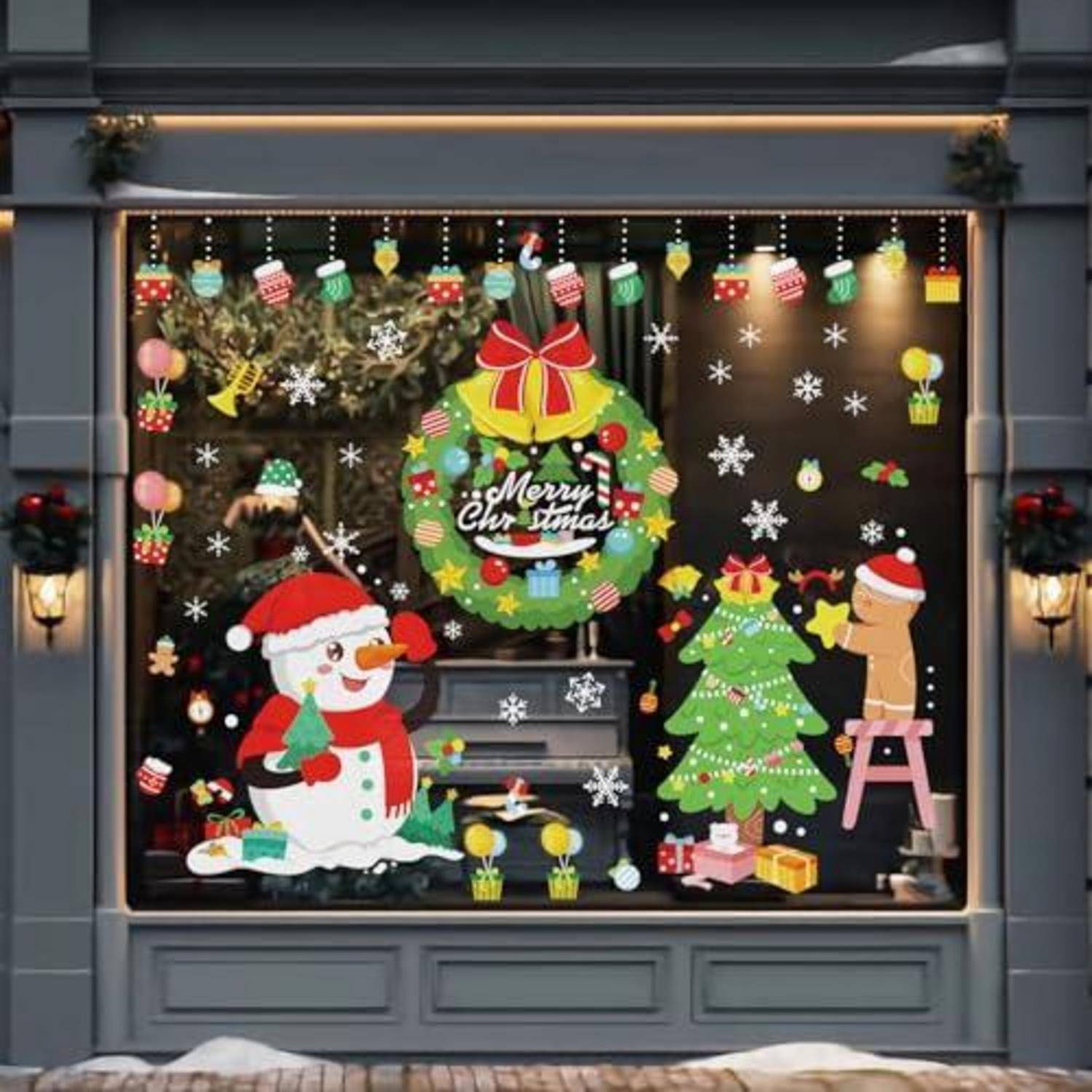 Weihnachtsschaufensterdisplay mit dem Weihnachtsmann, Kranz mit der Aufschrift "Frohe Weihnachten"", Schneemann, Baum, Geschenken und hängenden Ornamenten.