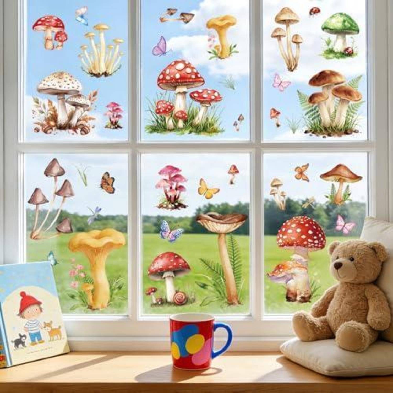 Fensterausstellung mit farbenfrohen Pilzillustrationen und Schmetterlingen, zu sehen über einem Teddybär eines Kindes, einer Tasse und einem Kissen auf einer sonnigen Fensterbank.