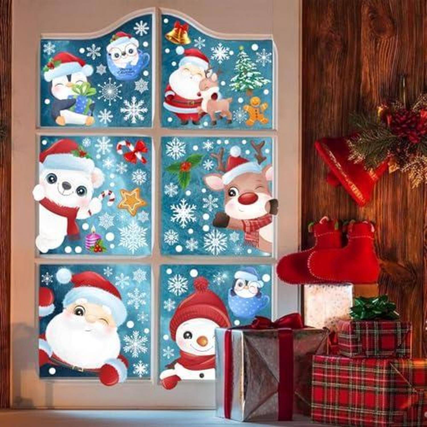Weihnachtsfensterdekoration mit sechs Cartoon-Feiertagspanelen, die den Weihnachtsmann, einen Eisbären, Rentiere, einen Schneemann und eine Eule inmitten von Schneeflocken zeigen; Geschenke hängen neben dem Fenster.