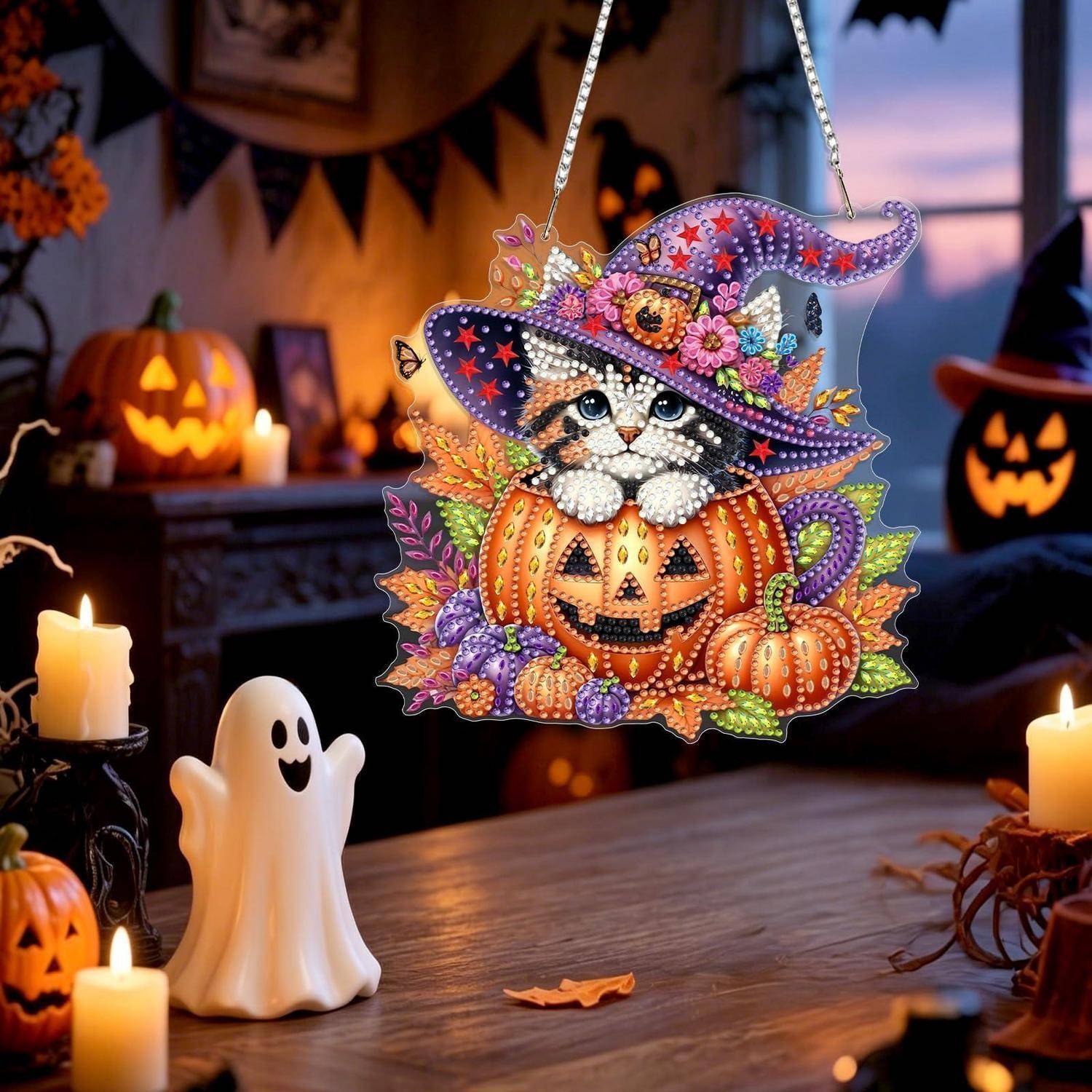 Halloween-Dekoration eines Kätzchens in einem geschmückten Hexenhut, das in einer Kürbislaterne sitzt, mit Kerzen und einem kleinen Gespenst auf einem Tisch.