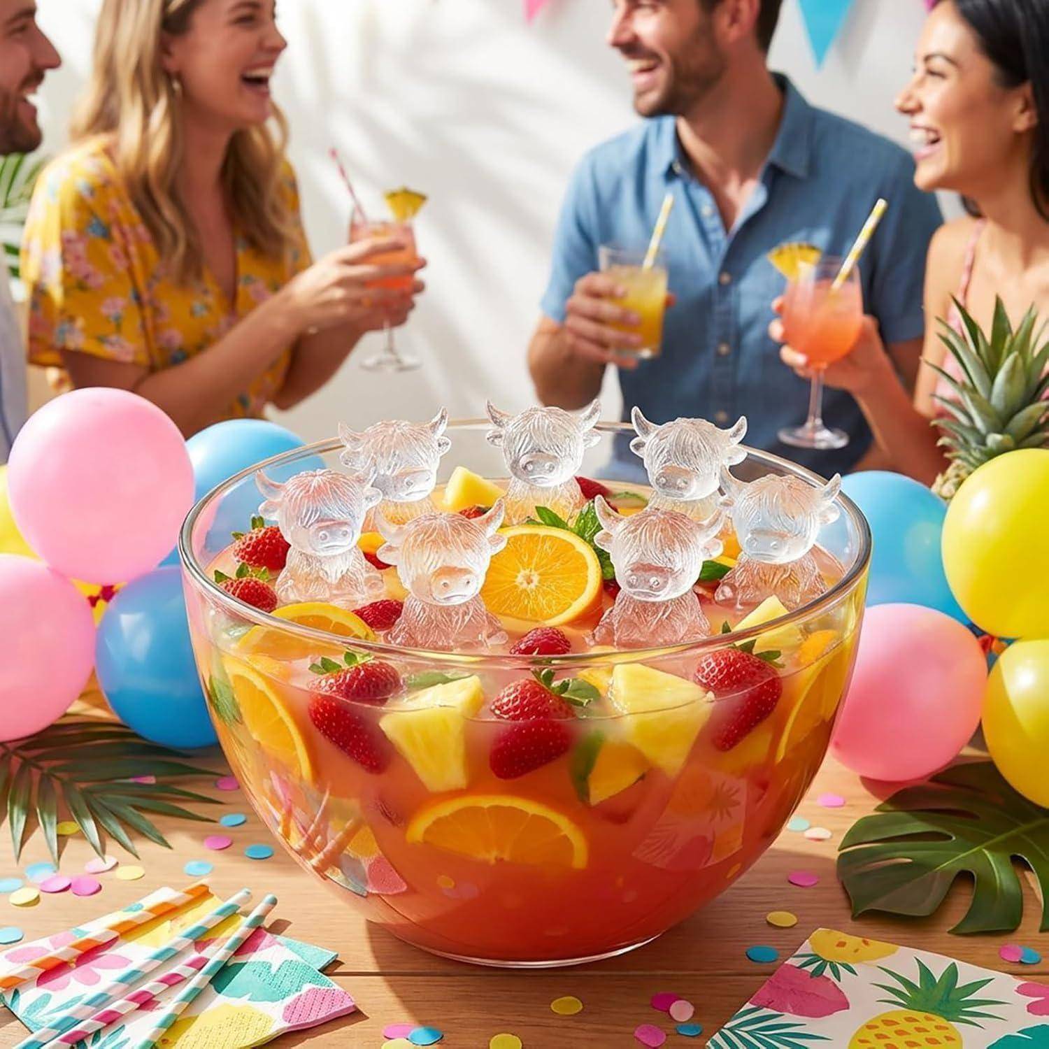 Ein Partytisch mit einer großen Schüssel Fruchtpunsch, gekrönt mit eisbärförmigen Eiswürfeln, umgeben von Ballons, Konfetti, Ananas und Menschen, die im Hintergrund Getränke halten.
