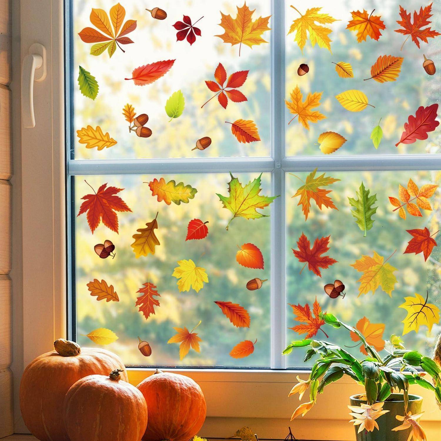 Herbstlich gestaltetes Fenster mit bunten fallenden Blättern und Eicheln, mit Kürbissen und einer Topfpflanze auf der Fensterbank.