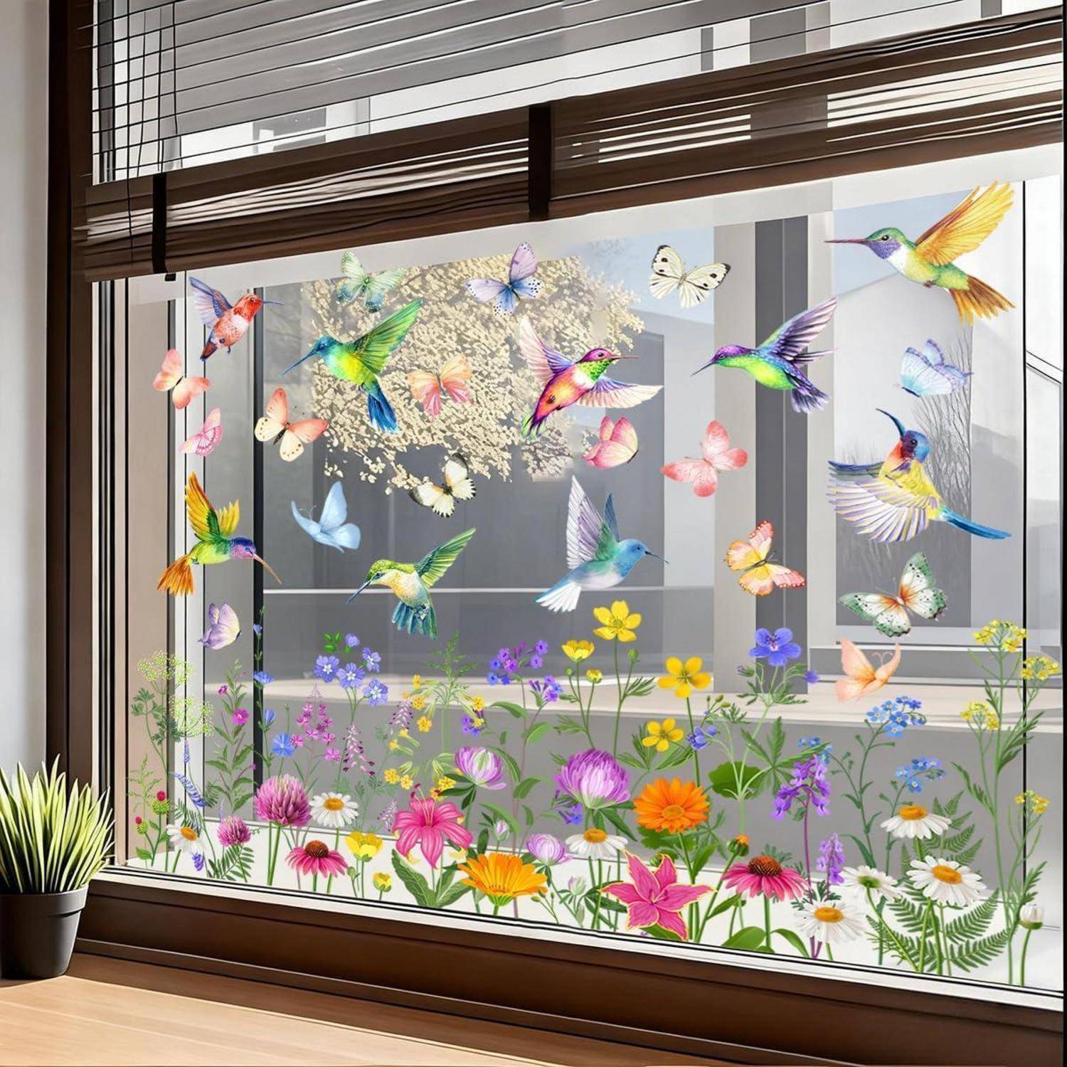Farbenfrohe Vogel- und Schmetterllings-Fensteraufkleber über einer Gartenszene mit Blumen und Kolibris auf einem großen Innenfenster.