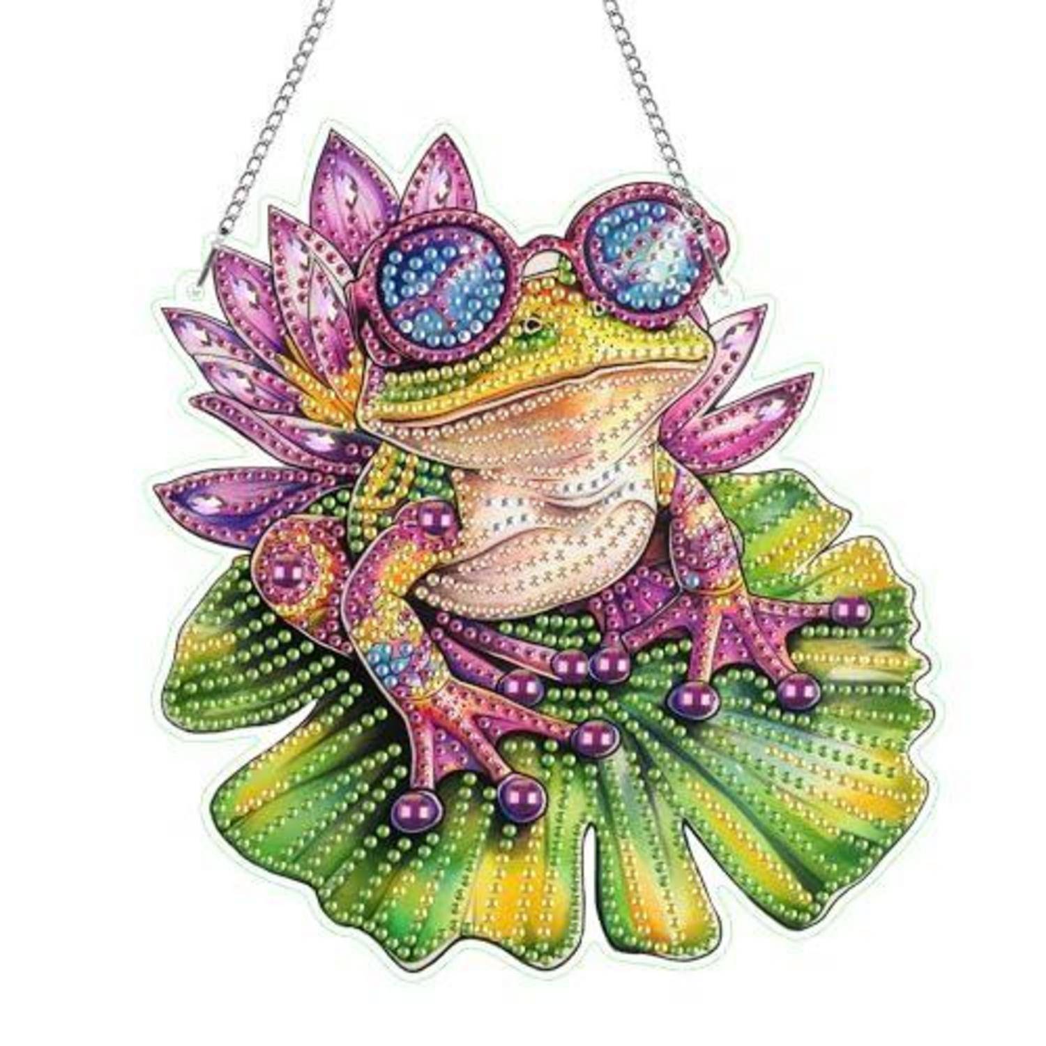 Ein buntes Perlen-Frosch-Ornament mit lotusähnlichen Blütenblättern und runden blauen Augen, das an einer Kette vor weißem Hintergrund hängt.