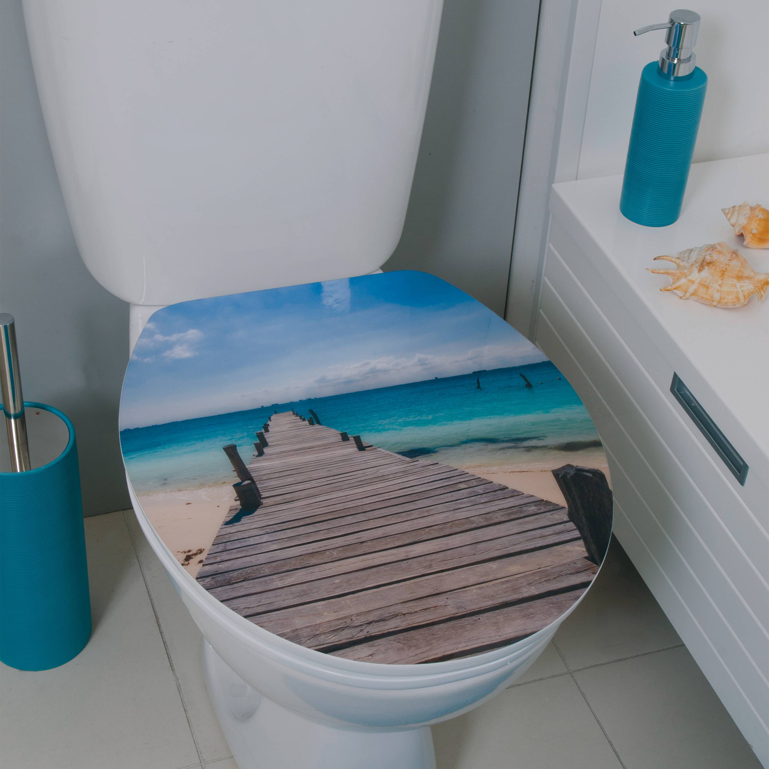 Toilette mit einer Strandstegartigen Sitzkissenbezug im Badezimmer, mit blauen Accessoires und Muscheln in der Nähe.