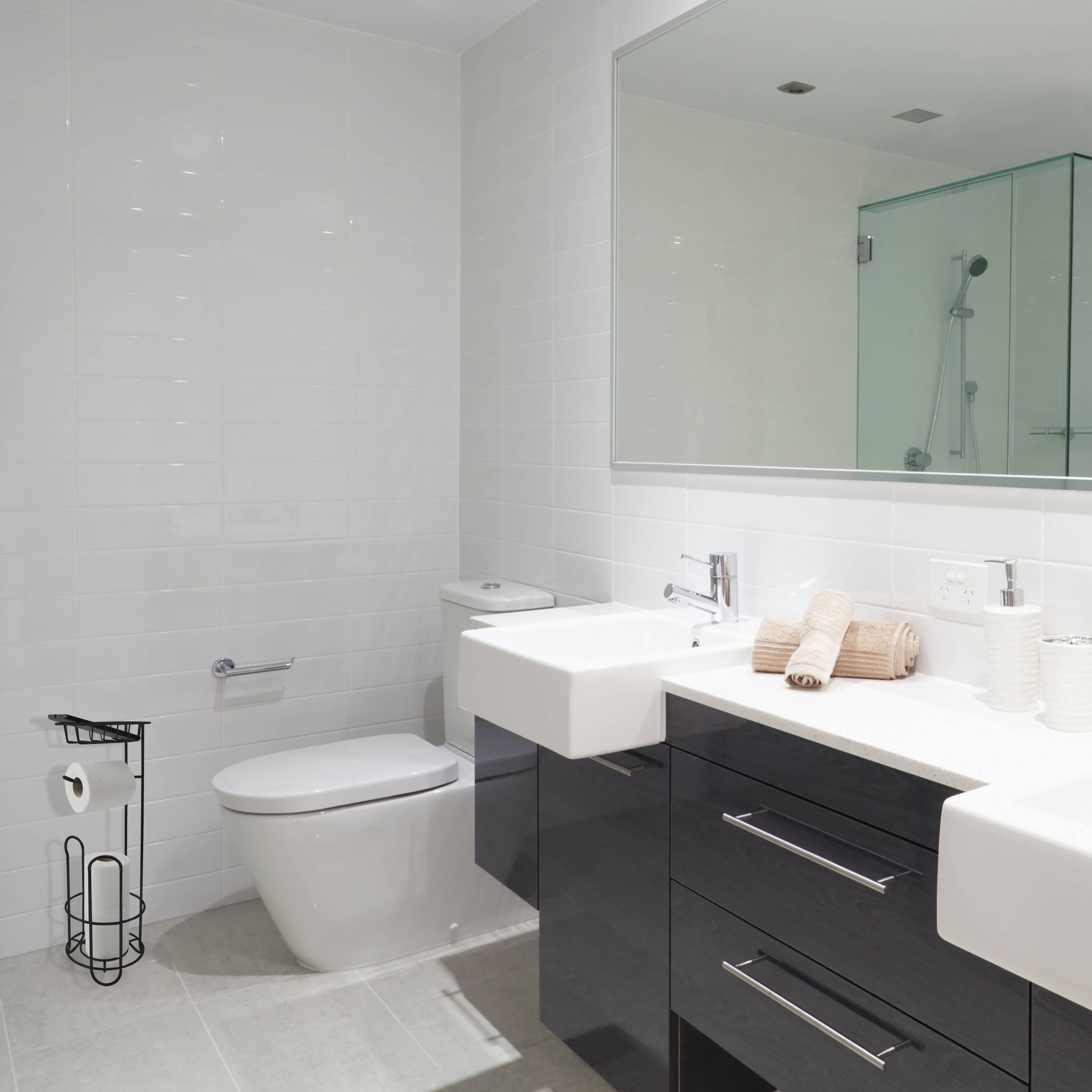 Modernes weißes Badezimmer mit Toilette, wandmontiertem Waschbecken, Waschtischschrank, Spiegel und Glasduschkabine.