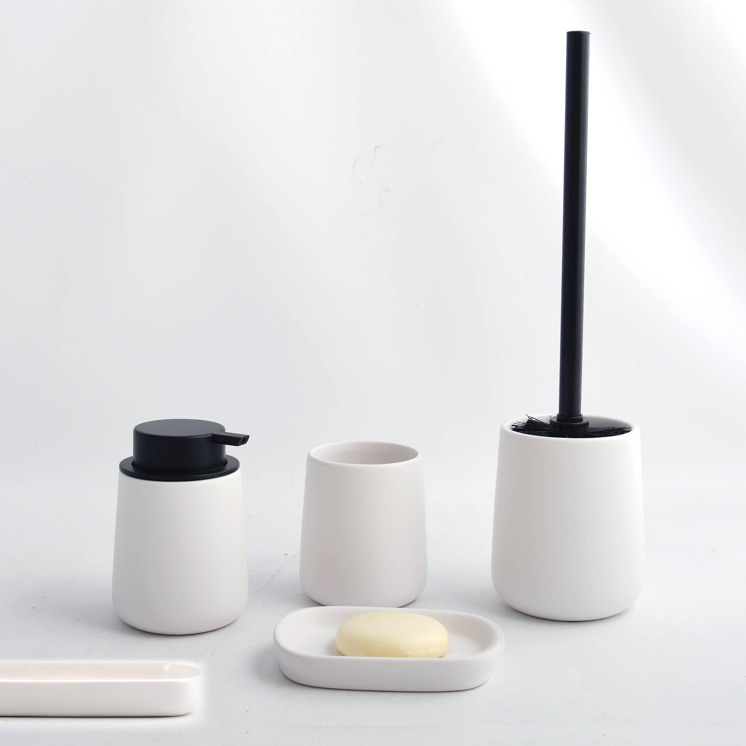 Minimales Badezimmerset mit weißen Keramikbehältern: ein Seifenspender, eine Zahnbürstenhalterung, eine Seifenschale und ein Toilettenbürstenhalter auf einer weißen Oberfläche.