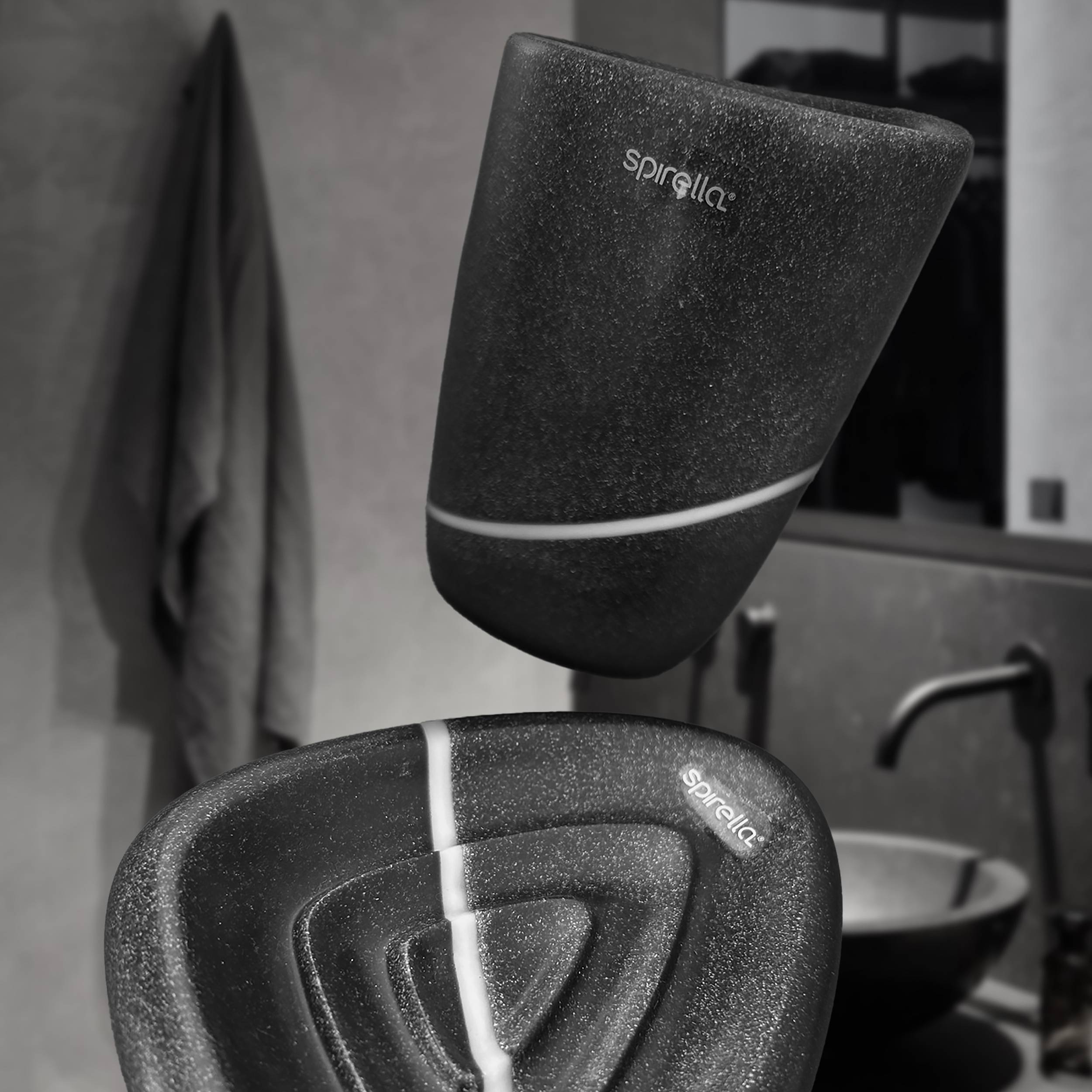 Zwei schwarze strukturierte Spirella-Badezimeraccessoires, ein wandmontierter Behälter über einer passenden Halterung, in einem modernen Badezimmer.