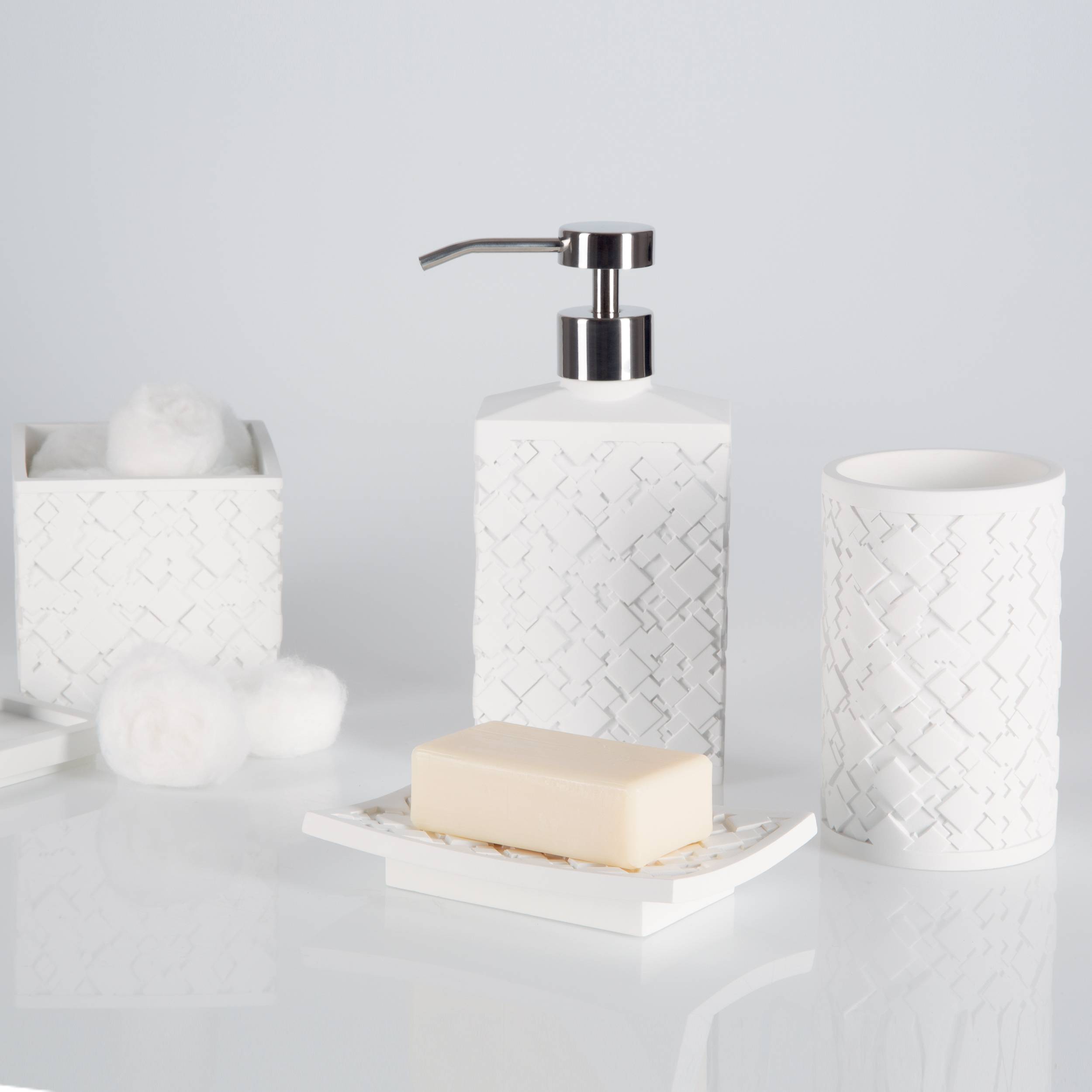 Weiße Badezimmeraccessoires-Set mit Seifenspender, Becher, Papierkorb, Seifenschale und Wattekugeln auf hellem Hintergrund.