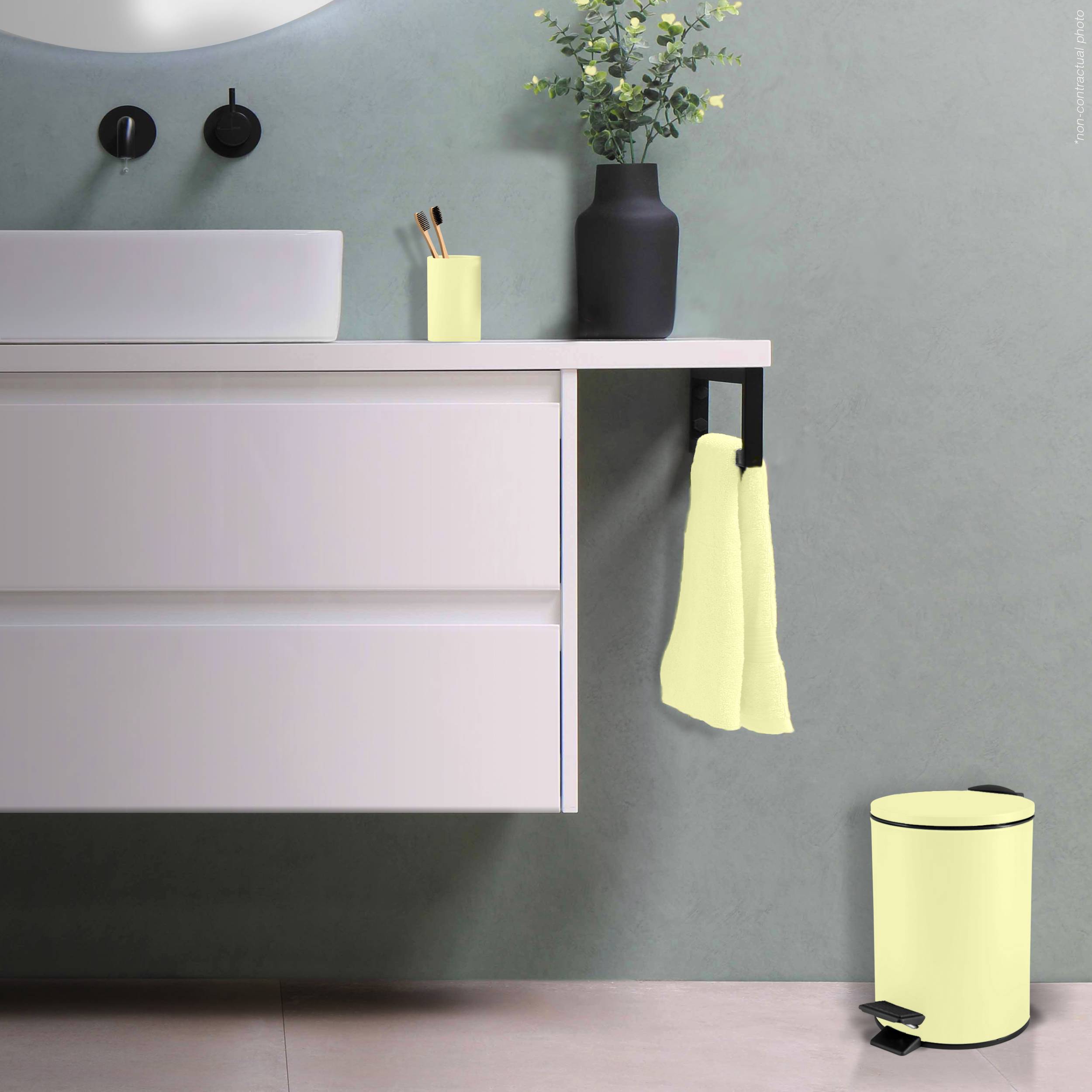 Modernes Badezimmermöbel mit Waschbecken und wandmontierten Handtüchern, schwarze Vase auf der Arbeitsplatte und ein entsprechender Trittabfallbehälter auf dem Boden vor einer grauen Wand.