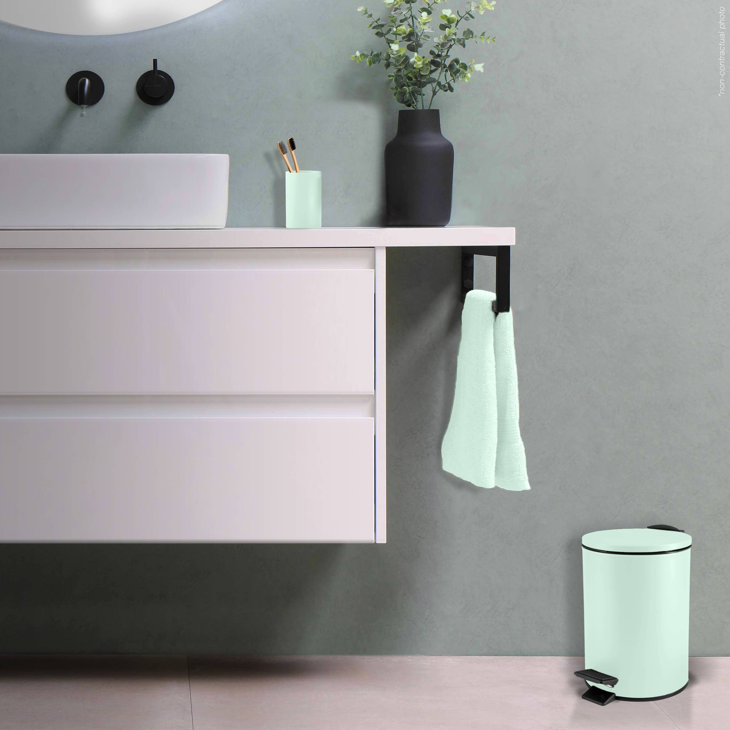 Modernes Badezimmermöbel mit Waschbecken, schwarzen Armaturen, mintfarbenen Accessoires, Vase, Handtuch und passendem Mülleimer vor einer grauen Wand.