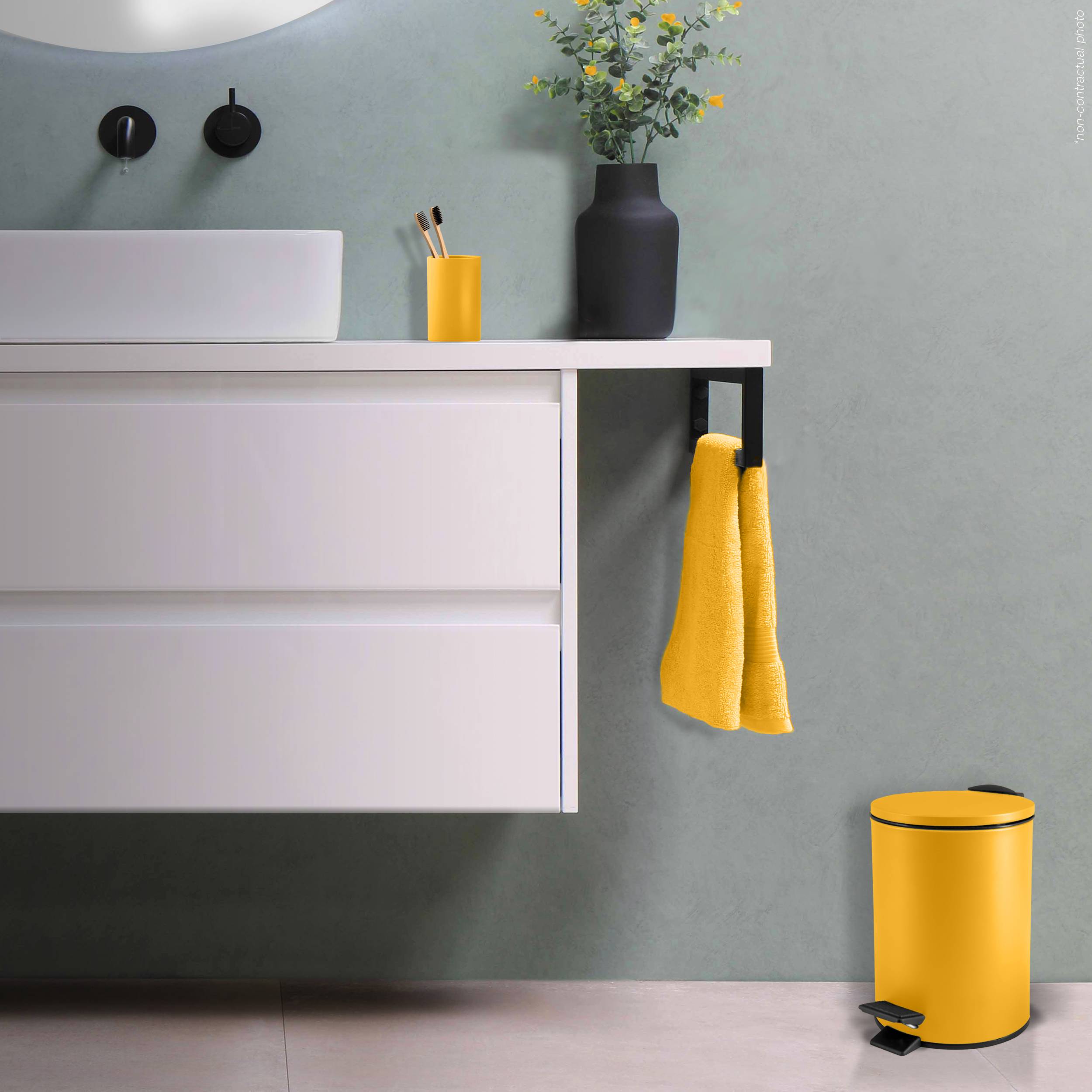 Modernes Badezimmer-Waschtisch mit weißem Spülbecken-Unterschrank, schwarzem Wasserhahn und Vase, gelbes Handtuch, das seitlich hängt, und passendem gelbem Mülleimer.