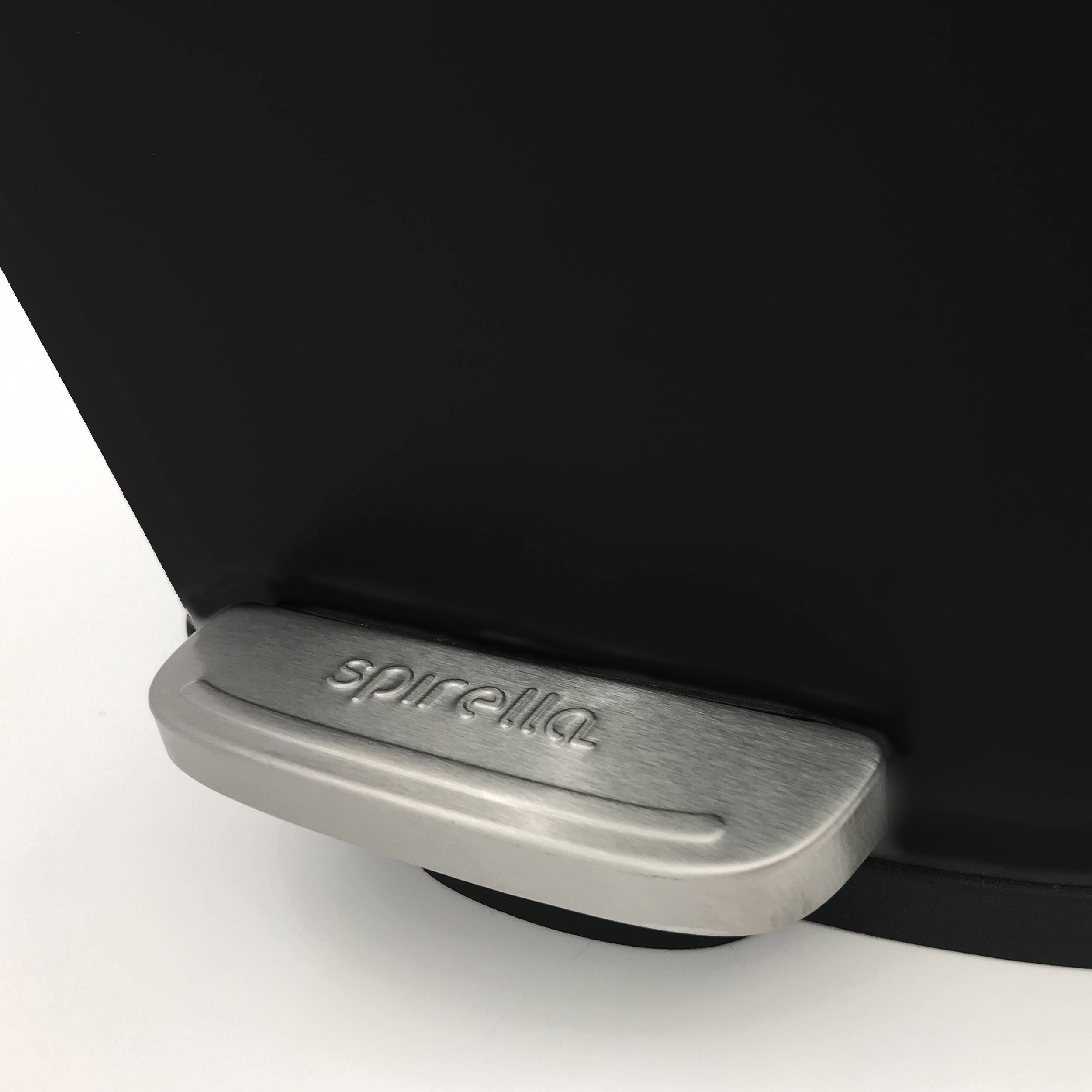 Nahaufnahme eines gebürsteten Metallfußpedals mit der Bezeichnung „sparella", angebracht an einem schwarzen Gerätesockel auf einer weißen Oberfläche.