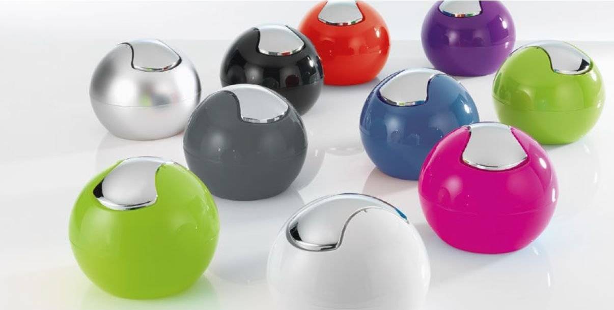 Glänzende farbenfrohe kugelförmige Objekte auf einer weißen Oberfläche, darunter silbern, schwarz, rot, lila, grün, blau, rosa und weiß.