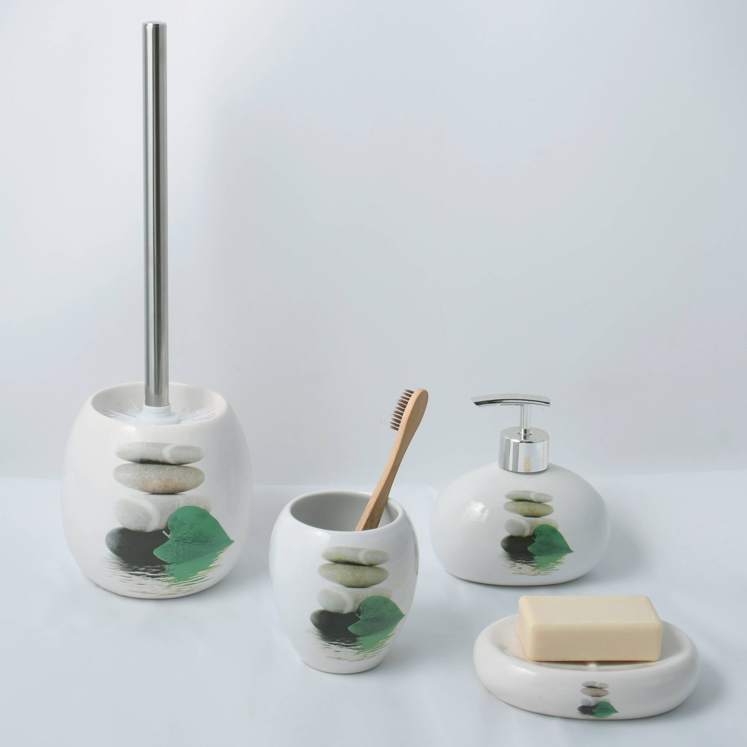 Weiße Keramik-Badezimmeraccessoires-Set mit Toilettenbürstenhalter, Zahnbürstenbecher, Seifenspender und Seifenschale, jeweils dekoriert mit grünen und grauen Steinen.