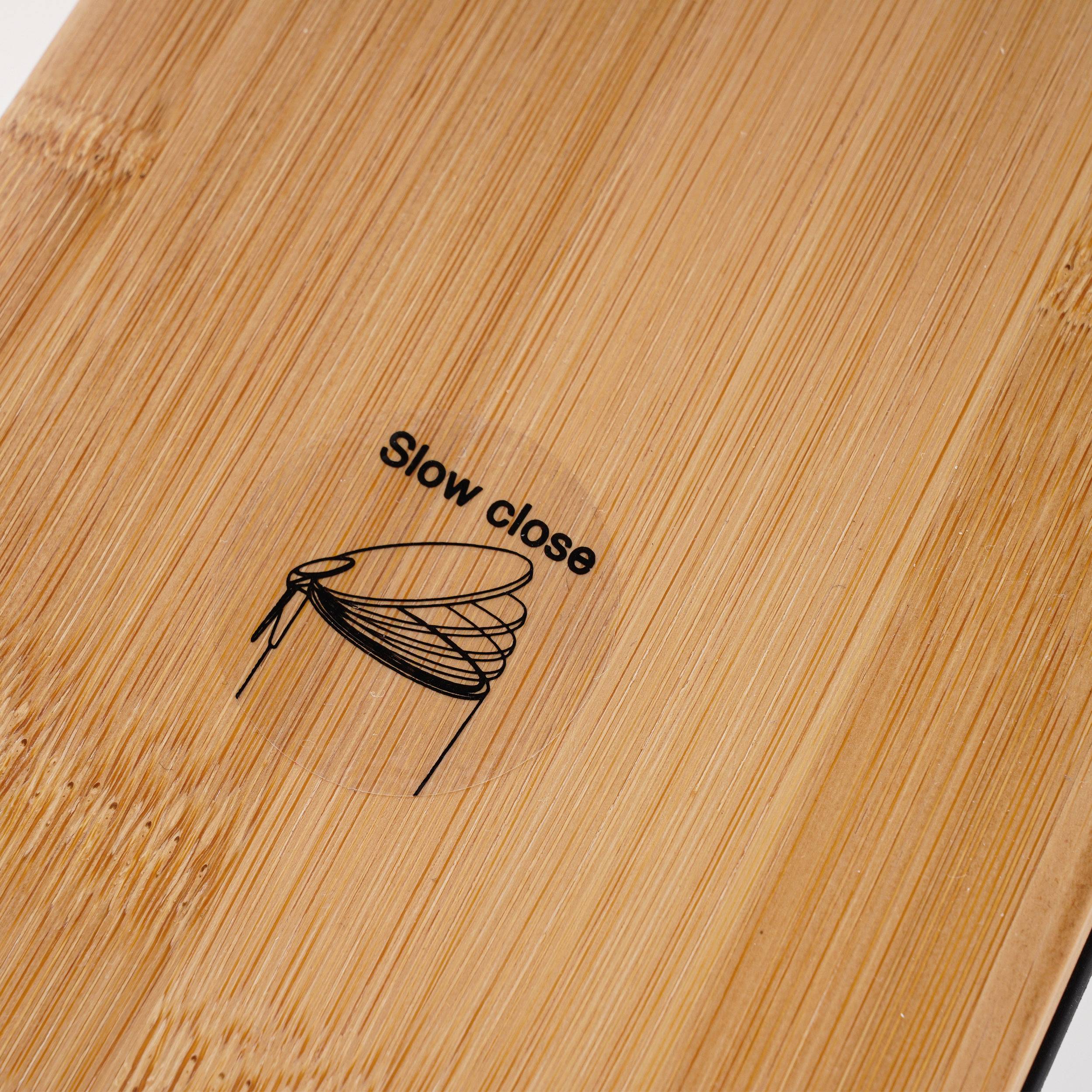 Nahaufnahme eines Bambus- oder Holzdeckels mit dem gedruckten Text „Slow Close