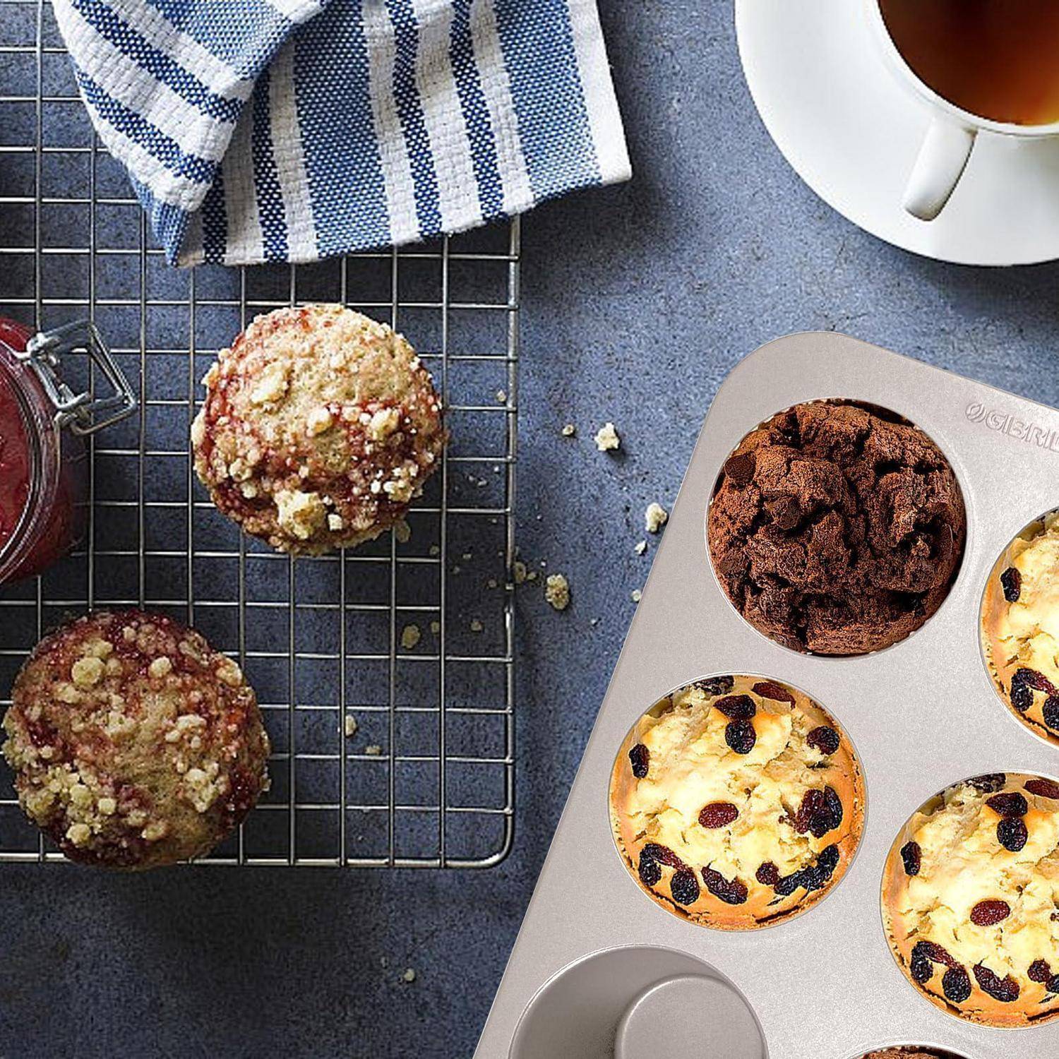 Aufsicht auf Muffins auf einem Abkühlgitter und in einer Muffinform neben einer Tasse Kaffee und einem gestreiften Handtuch.