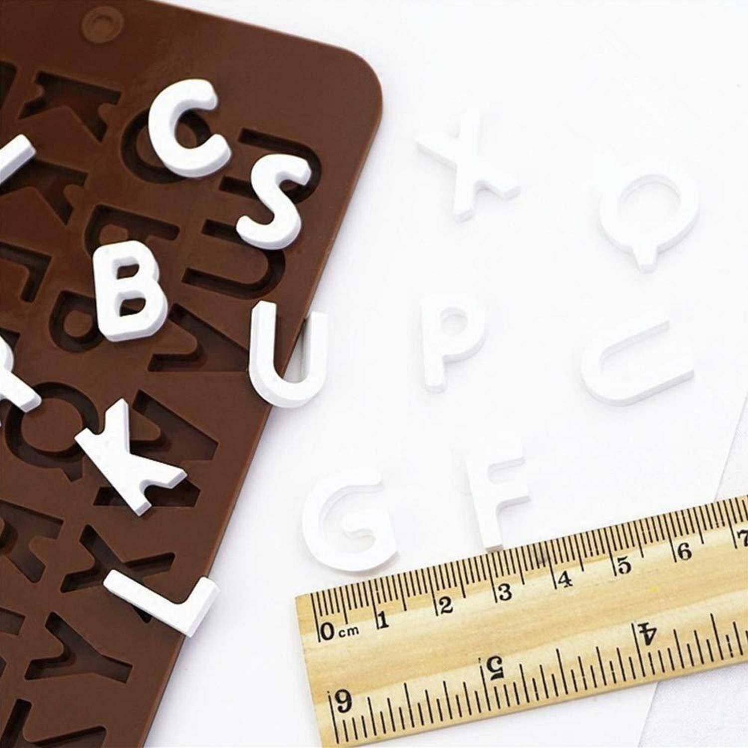 Brauner Briefschablone mit verstreuten weißen Kunststoffbuchstaben und einem Lineal auf weißem Hintergrund, was auf eine Alphabet- oder Typografieaktivität hindeutet.
