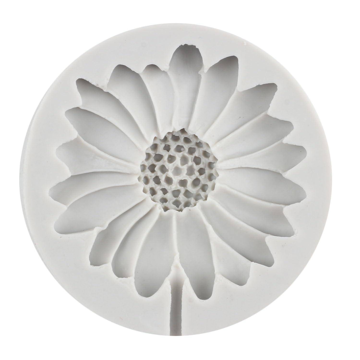 Weiße, kreisförmige Reliefplastik einer gänseblümchenähnlichen Blume mit geschichteten Blütenblättern und strukturiertem Mittelpunkt auf einfachem Hintergrund.