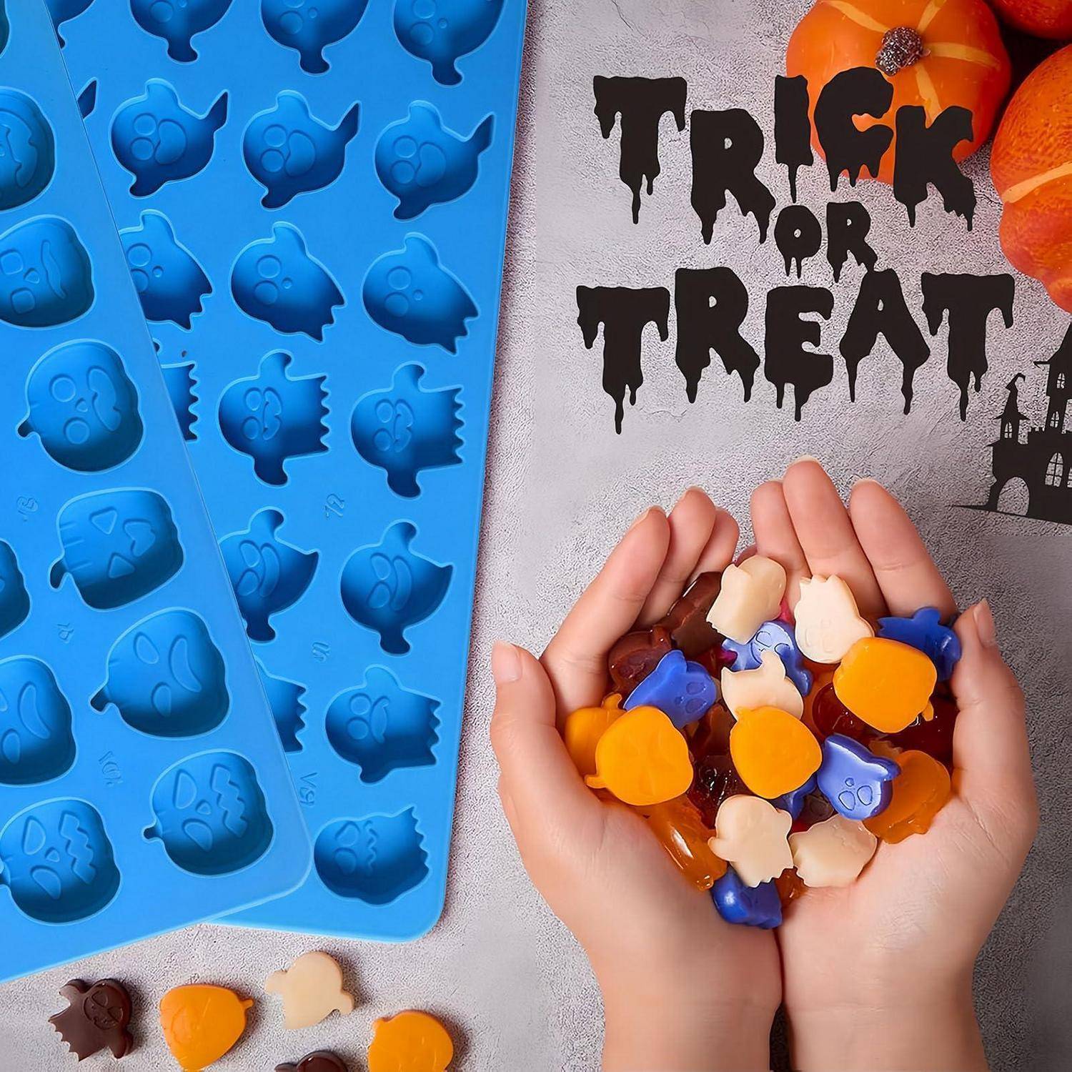 Hände halten Halloween-förmige Gummibonbons neben einer blauen Silikonform, mit 