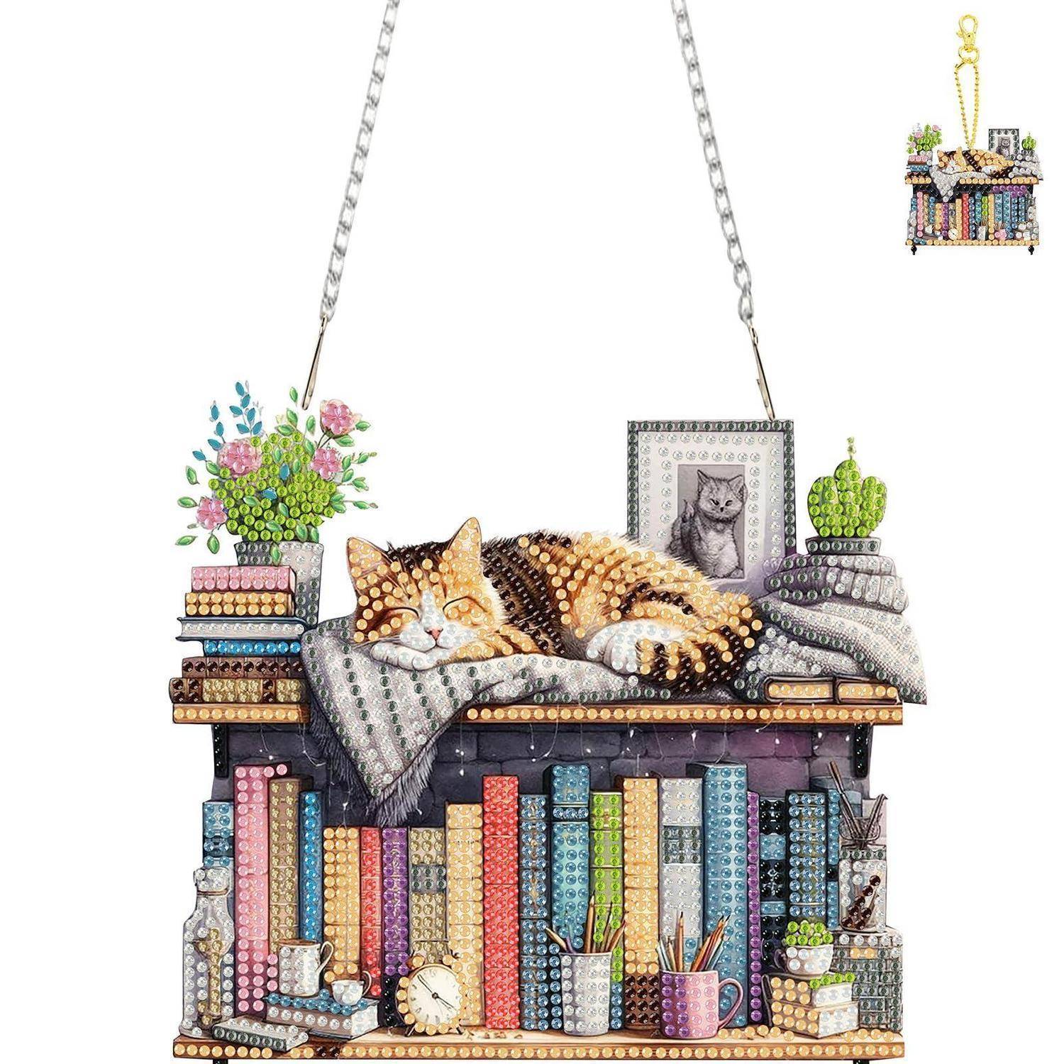 Diamantmalerei einer schlafenden Katze auf einer Bücherregal-Schaukel, mit Blumen, gerahmtem Katzenfoto, Kaktus, Büchern und Kunstbedarf.
