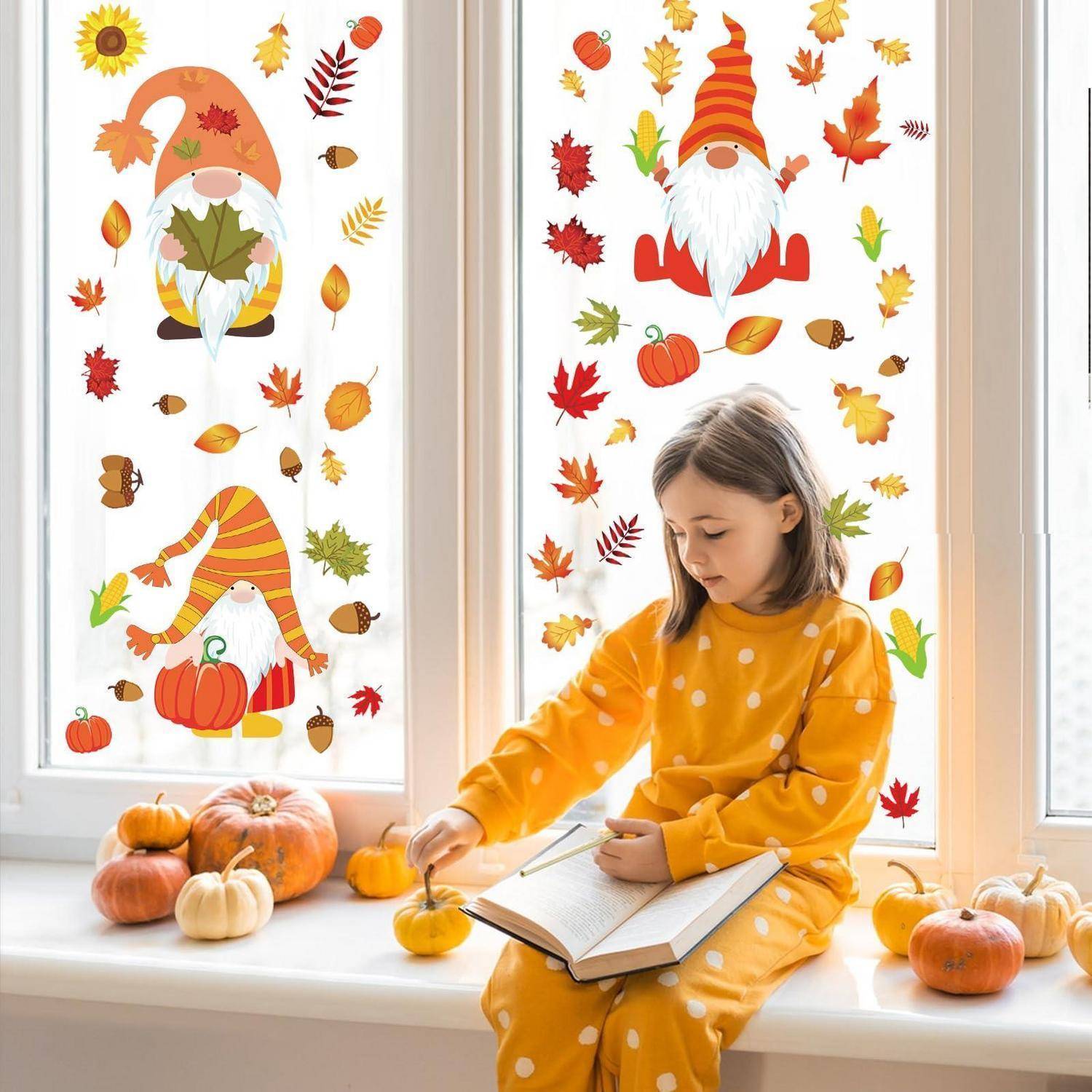 Mädchen in gelbem Outfit mit weißen Punkten sitzt auf einer Fensterbank beim Lesen, umgeben von Kürbissen und Herbst-Gnomen- und Blatt-Fensteraufklebern.
