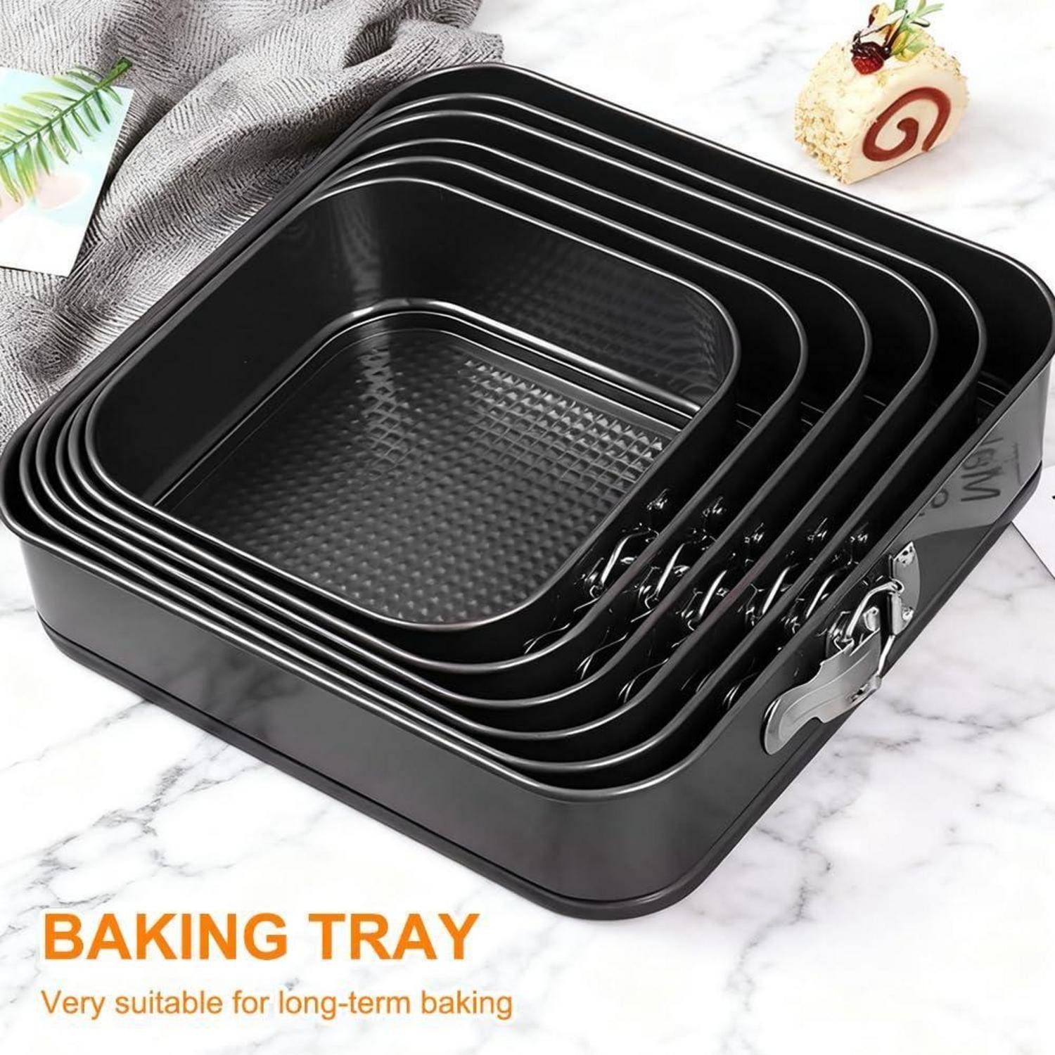 Stapel aus verschachtelten quadratischen schwarzen Backblechen mit Metallverschlüssen auf einer Marmoroberfläche, beschriftet mit „BACKBLECH" und „Sehr geeignet für langfristiges Backen"".