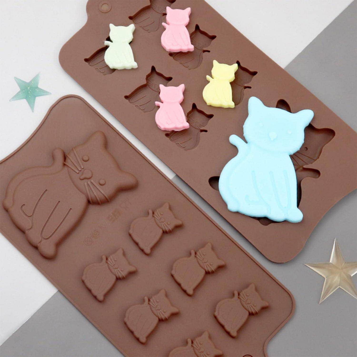 Zwei braune Silikon-Katzenprägen mit pastellfarbenen Katzenbonbons oder Seifen in Rosa, Mint, Gelb und Blau, auf hellem Hintergrund präsentiert.