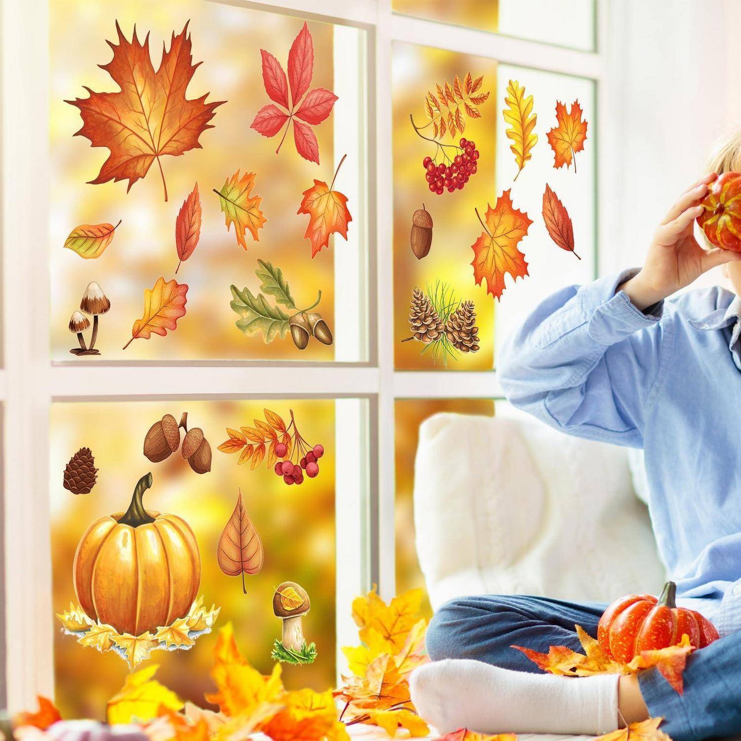 Kind, das neben einem Fenster sitzt, das mit Herbstlaubausschnitten und Erntedekorationen geschmückt ist, hält einen kleinen Kürbis und ist von Herbstblättern und Kürbissen umgeben.