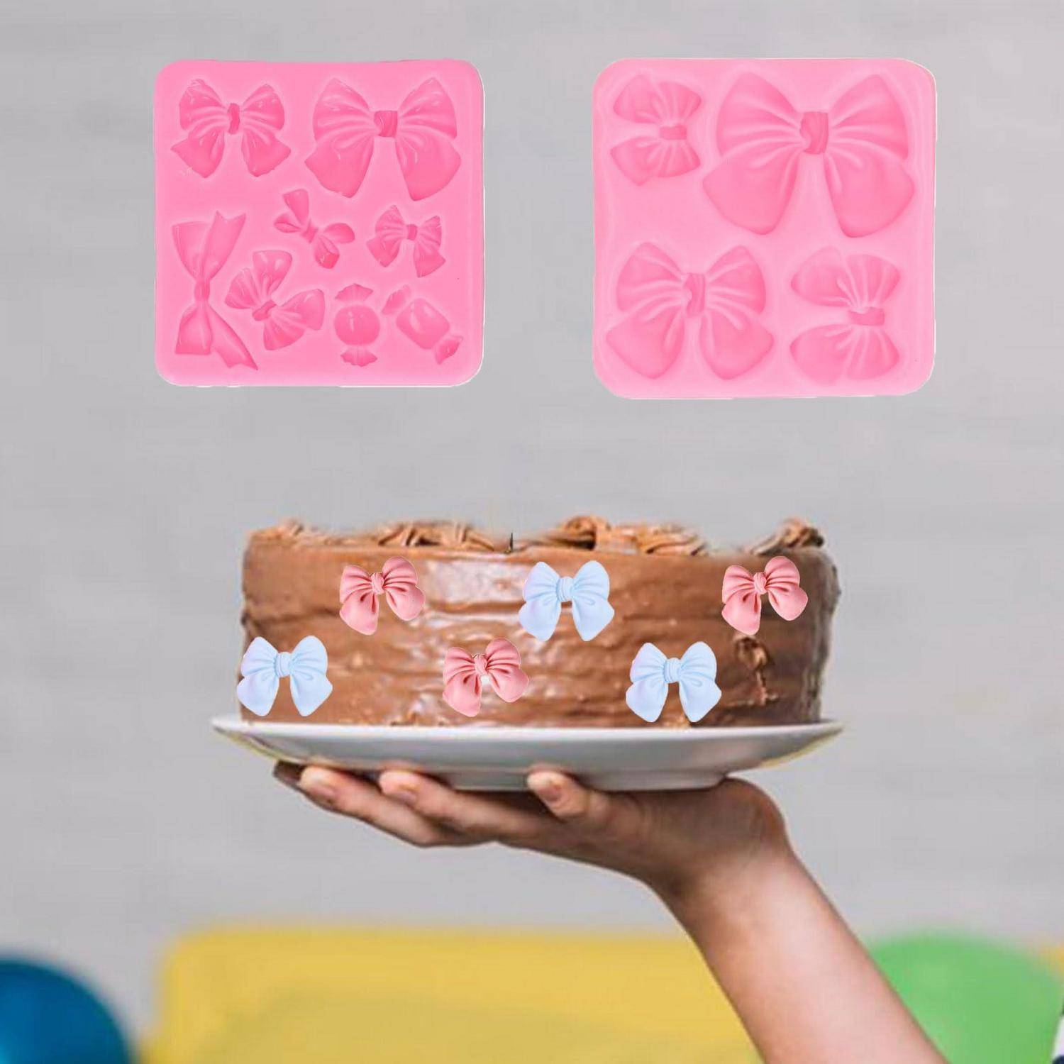 Eine Hand hält einen Schokoladenkuchen, der mit rosafarbenen und blauen Schmetterlings-Toppern verziert ist, mit zwei rosafarbenen Schmetterlings-Silikonformen, die oben gezeigt werden.