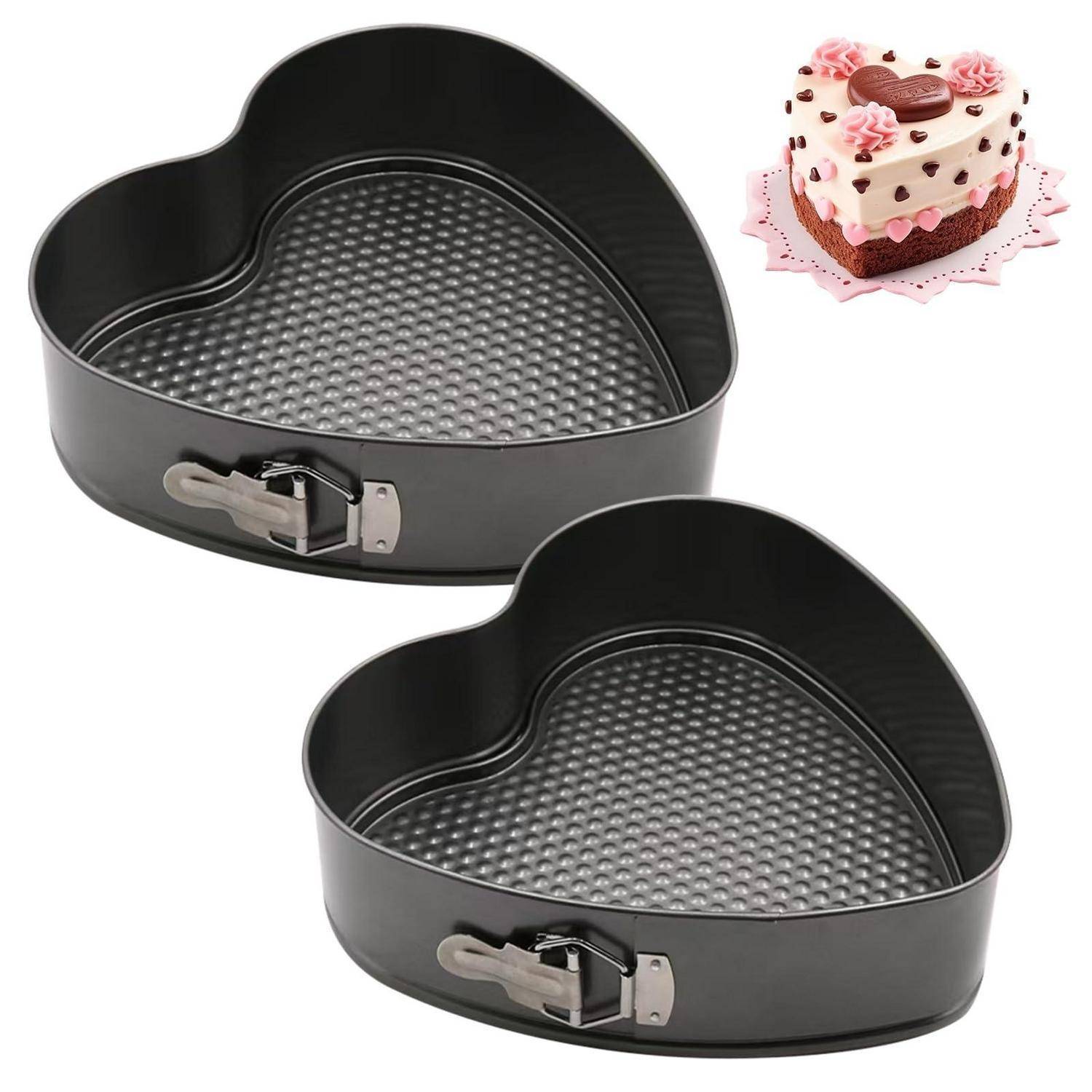 Zwei herzförmige Springformen mit rutschfester strukturierter Oberfläche, dargestellt neben einem dekorierten herzförmigen Kuchen.