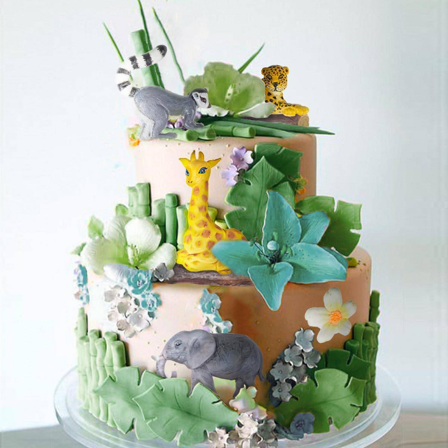 Zweistöckiger Dschungel-Thema-Kuchen, verziert mit einer Giraffe, einem Elefanten, einem Lemur, einem Leoparden und großen grünen Blättern und Blumen.