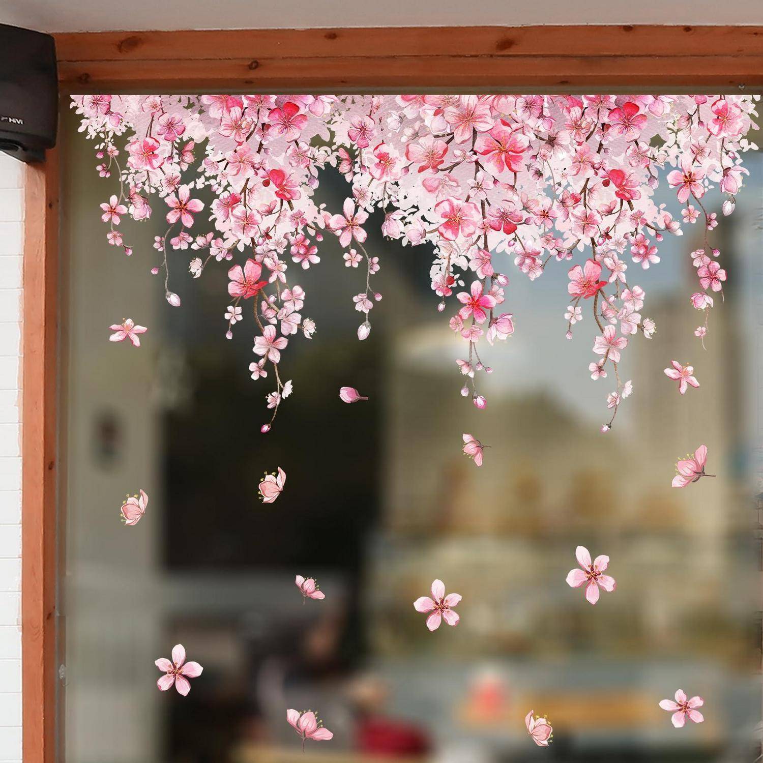 Rosa Kirschblüten-Aufkleber hängen über einem Glasfenster oder einer Glastür und schaffen eine dekorative Blütenborte mit verstreuten Blütenblättern.