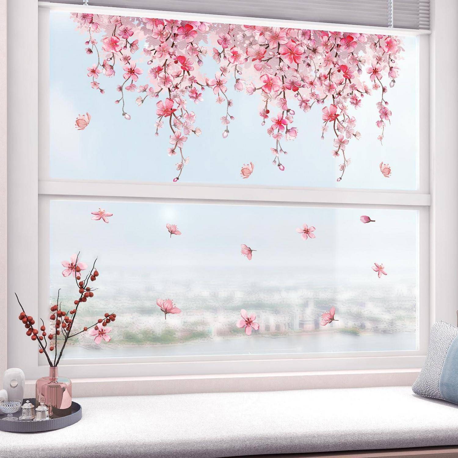 Fenster mit rosa Kirschblüten-Aufklebern, einschließlich hängender Zweige auf der oberen Scheibe und verstreuten Blütenblättern auf der unteren mattierte Scheibe.