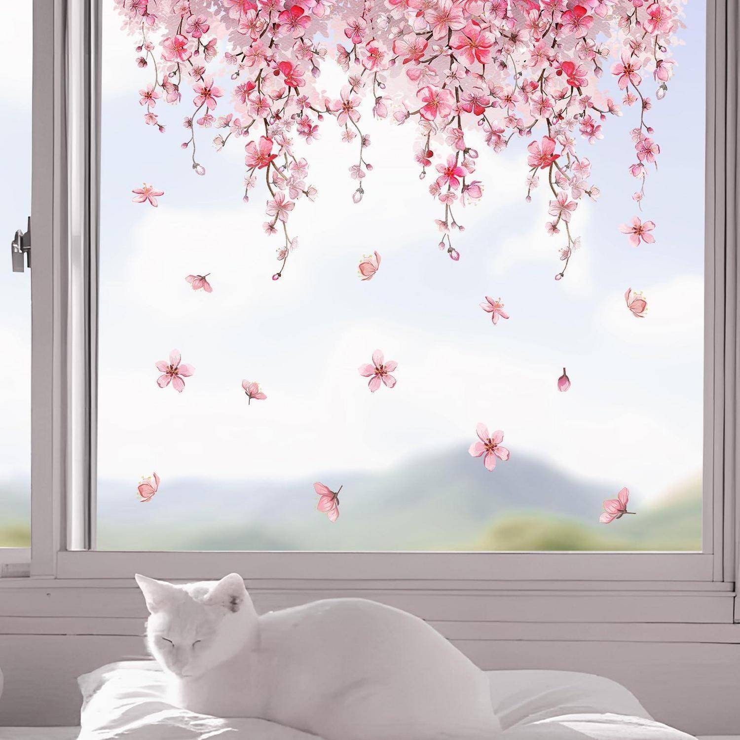 Eine weiße Katze schläft auf einem Kissen neben einem Fenster, während rosa Kirschblüten außen hängen und vorbeischweben vor einem sanften Himmel und fernen Hügeln.