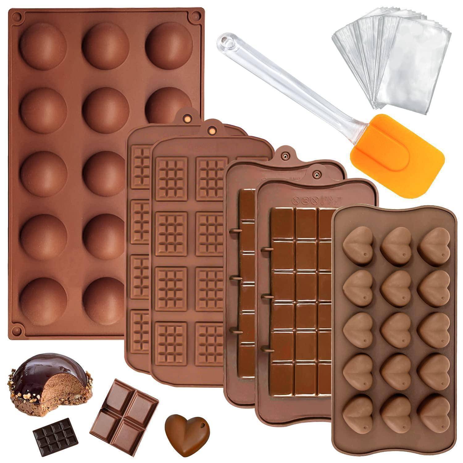 Sortierte Schokoladenformen und Backwerkzeuge: Silikonschalen für Trüffel, Herzen, Riegel und Waffeln, plus Spatel und Spritzbeutel.