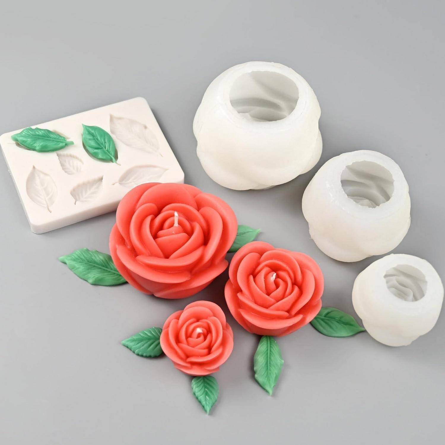 Silikonform und fertige rosenförmige Kerzen in Rot und Weiß mit grünen Blättern auf einer grauen Oberfläche.