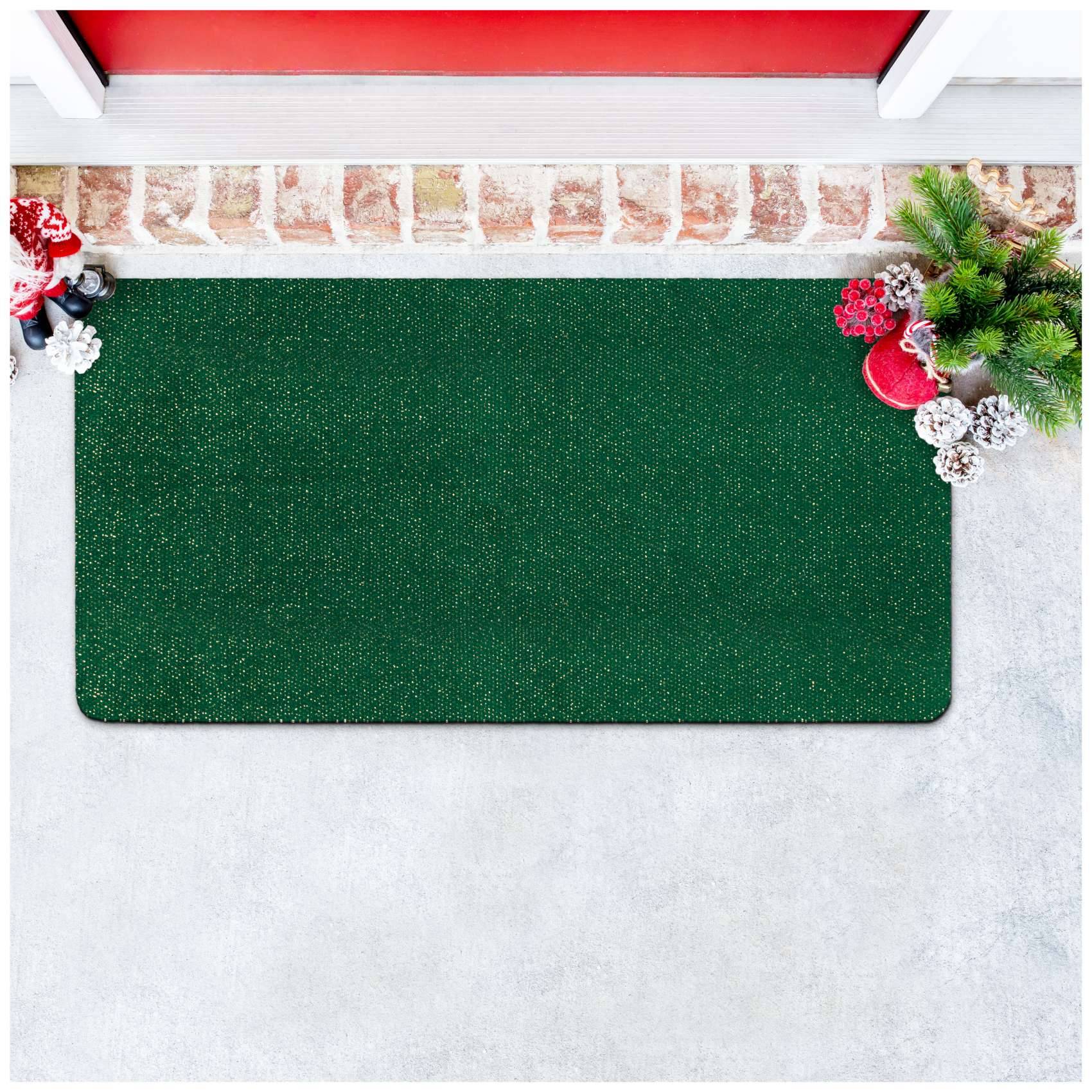 Leere grüne Fußmatte mit Weihnachtsdekoration in den oberen Ecken auf einem hellen Porenboden.