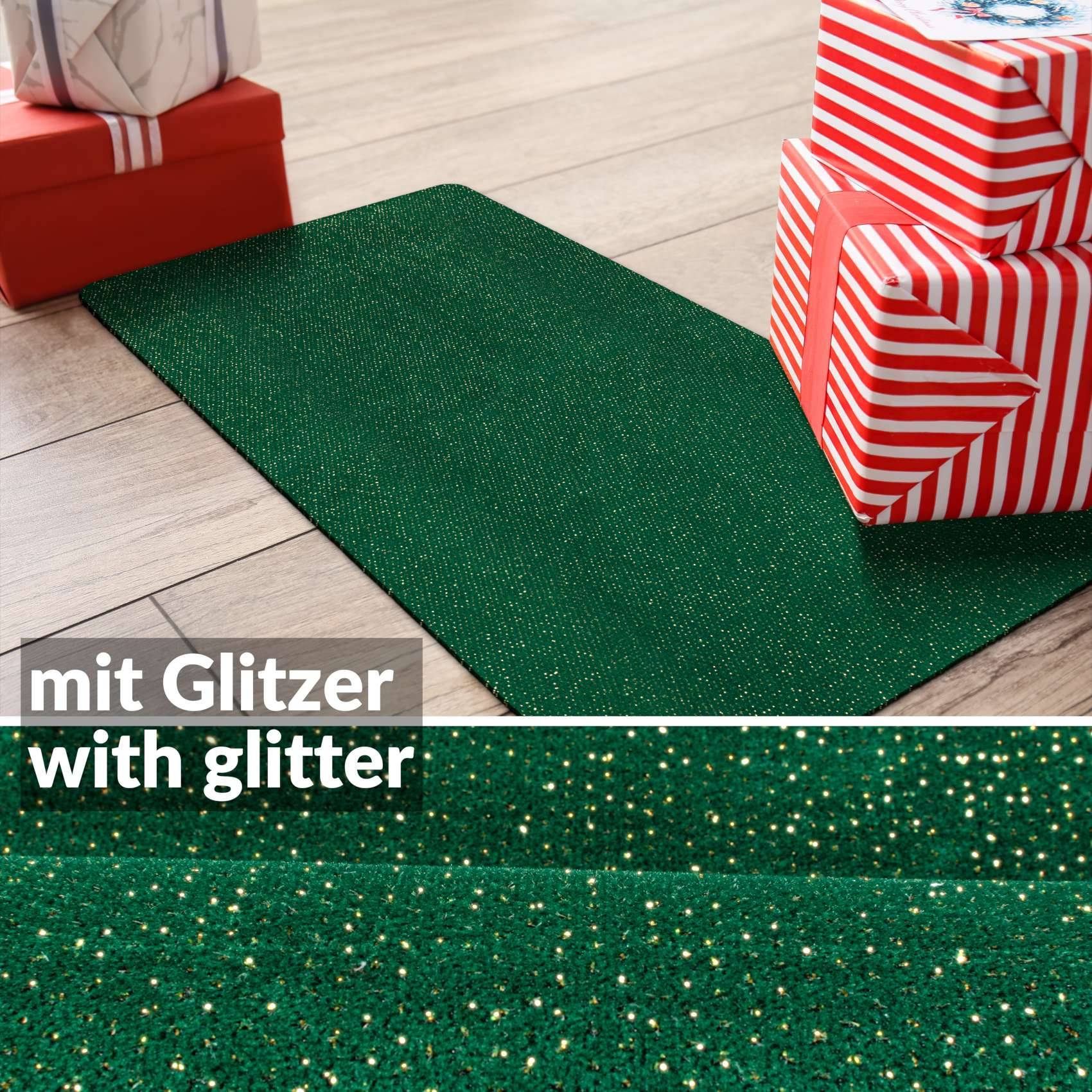 Grüne glitzernde strukturierte Matte oder Geschenkpapier neben verpackten Geschenkboxen auf einem Holzboden, mit dem Text „mit Glitzer" und „with glitter"".