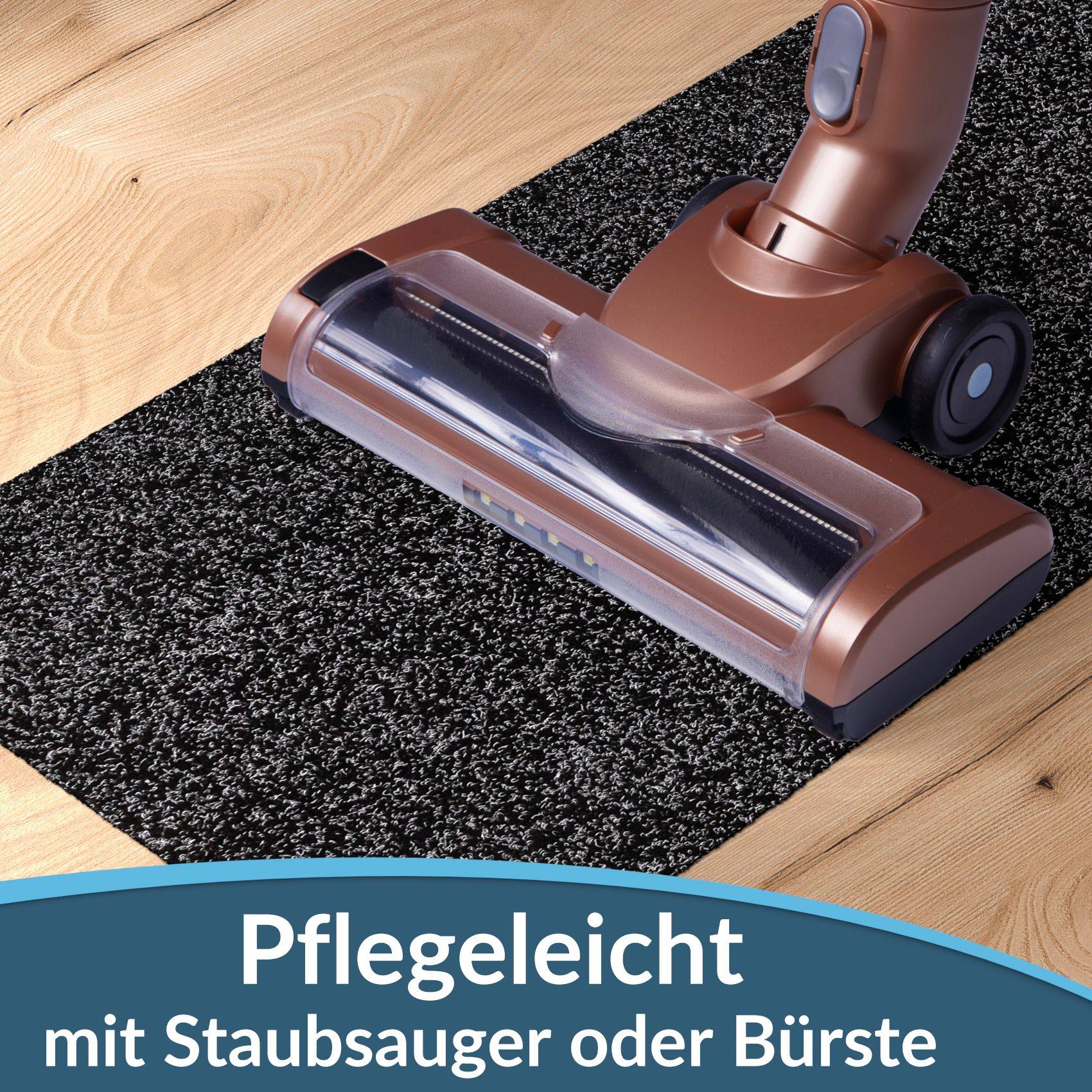 Teppichreinigungssaugkopf auf einem Teppich auf einem Holzfußboden, beschriftet mit „Pflegeleicht mit Staubsauger oder Bürste" (leichte Reinigung mit Staubsauger oder Bürste).