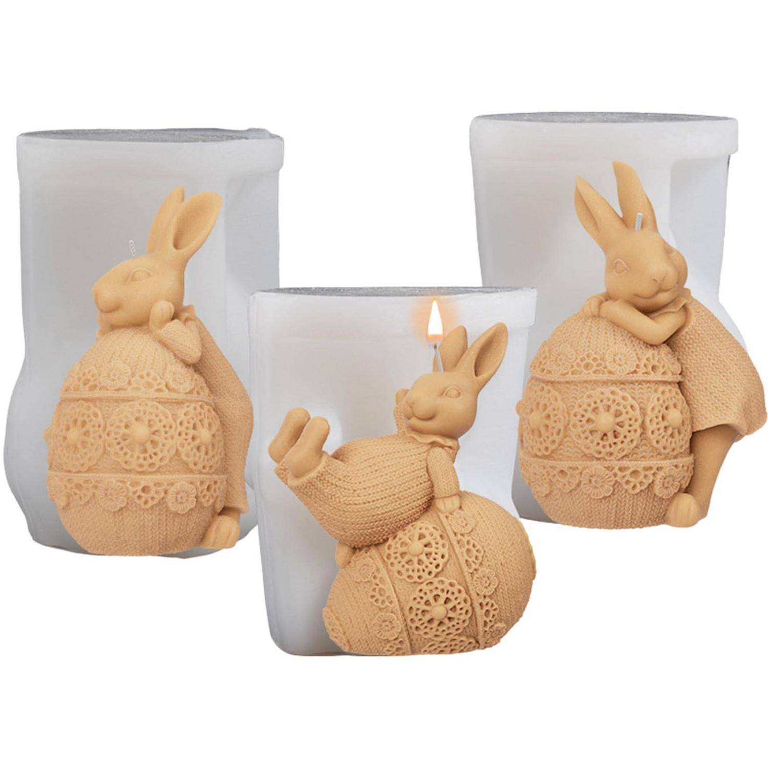 Drei Kerzenhalter aus mattiertem Glas mit dekorativen Hasenffigurinen; die mittlere Kerze ist angezündet, die anderen sind nicht angezündet.