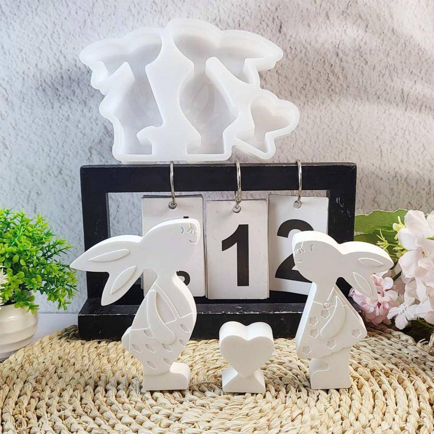 Dekorativer Kaninchen-Tischkalender mit der Nummer 12, mit weißen Hasenfiguren und einer kleinen Herzornament.