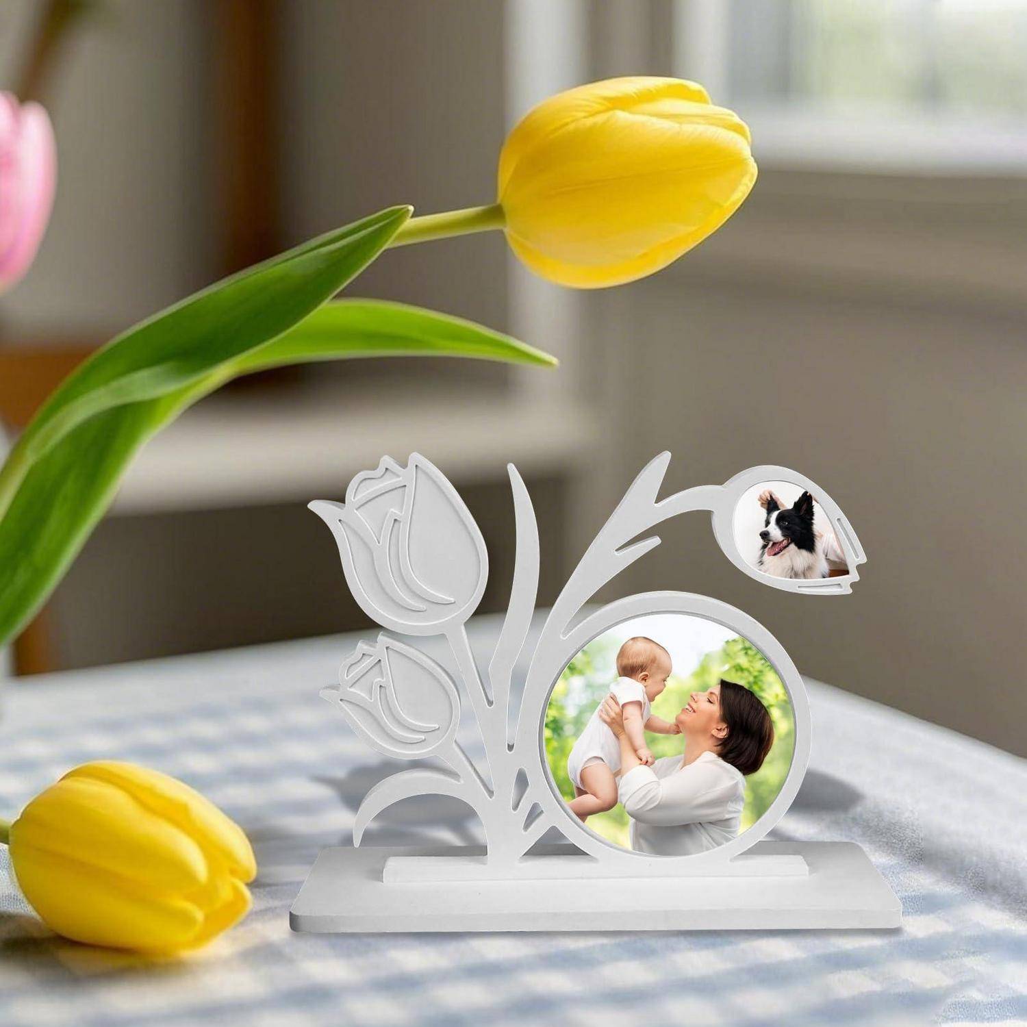 Weißer Blumenbilderrahmen mit einem Foto einer Mutter, die ein Baby hochhebt, mit einem kleinen Hundefoto als Einsatz und Tulpendekorationen auf einem Tisch.
