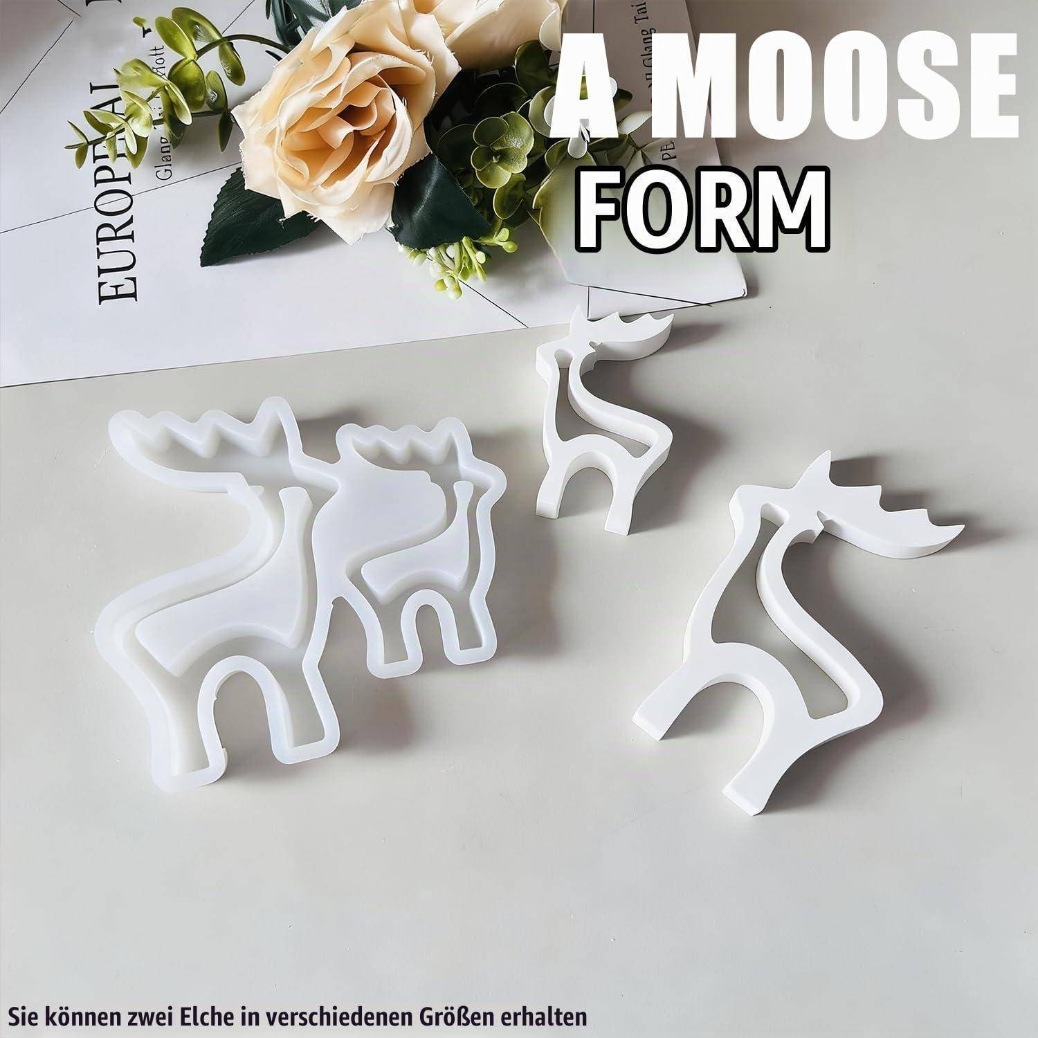 Weiße elchförmige Formen in verschiedenen Größen auf einem Tisch ausgestellt, mit der Beschriftung „A MOOSE FORM".