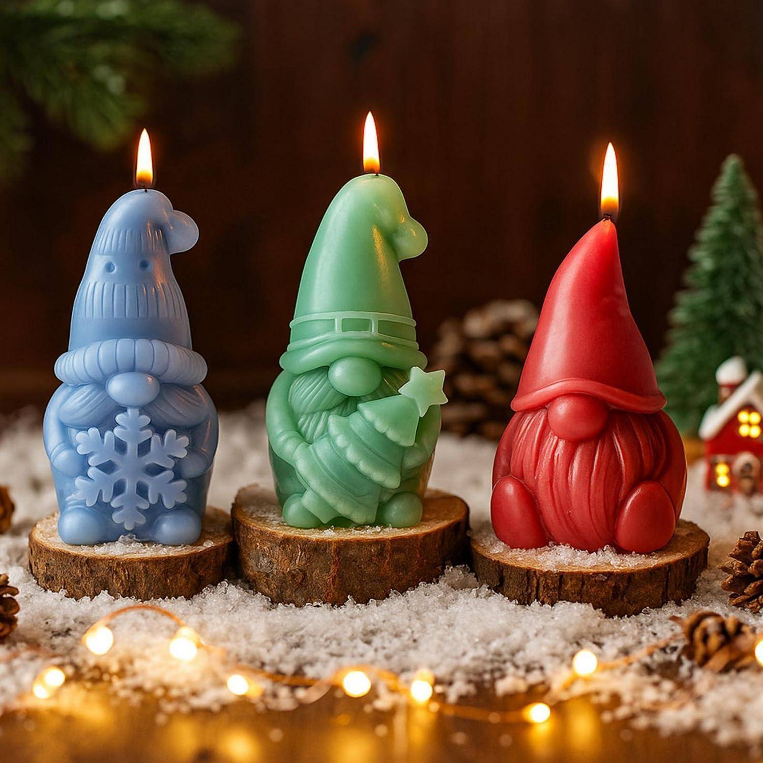 Drei brennende Kerzen in Gnomenform in Blau, Grün und Rot stehen auf Holzscheiben mit verschneiter Weihnachtsdekoration und Lichtern.