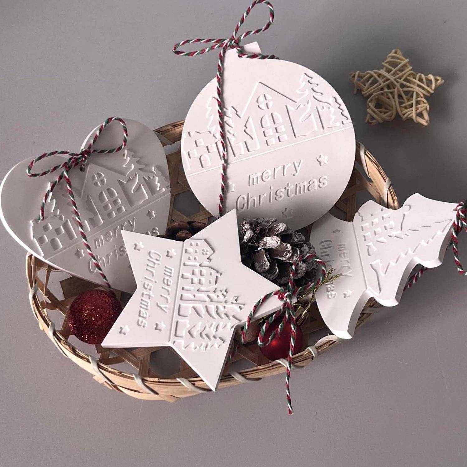 Korb mit weißen Weihnachtsgeschenkanhängern und Verzierungen mit der Aufschrift „Frohe Weihnachten", gebunden mit rot-weiß gestreiftem Band und Tannenzapfen.